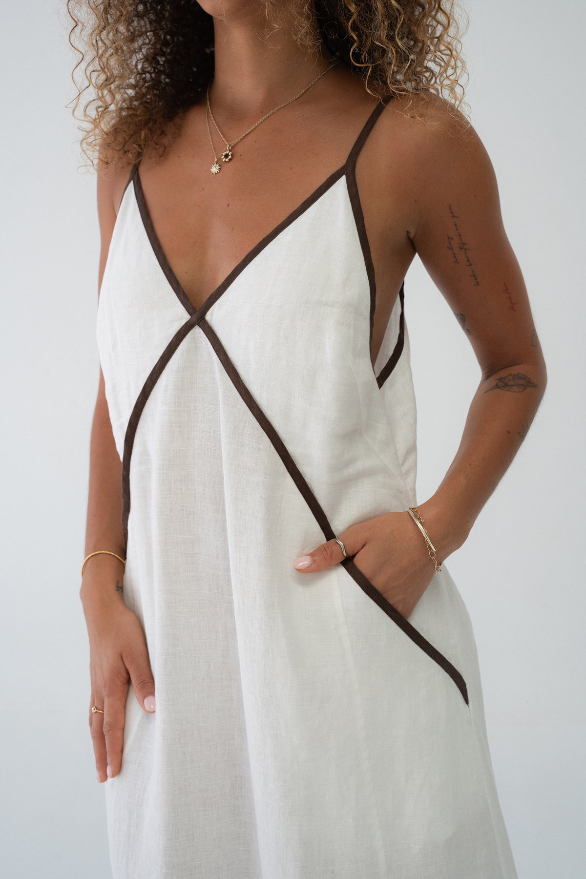 Azalea Linen Maxi Dress in Ivory - close-up of V-neckline and contrast cross-body trim, hand in pocket - Lilly Pilly Collection