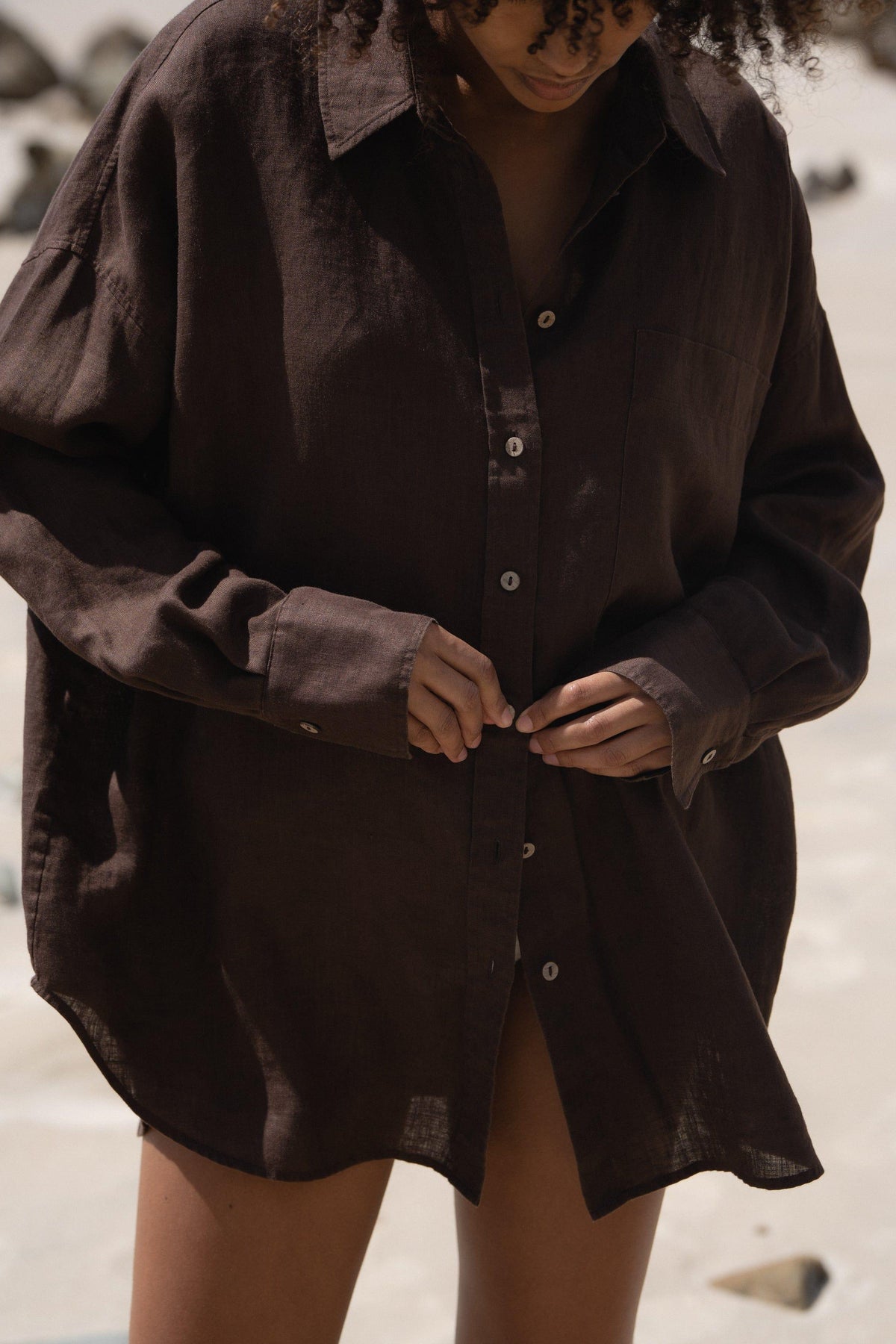 Kirra Linen Shirt in Chocolate - close-up, button-front detail, buttoning, beach backdrop - Lilly Pilly Collection