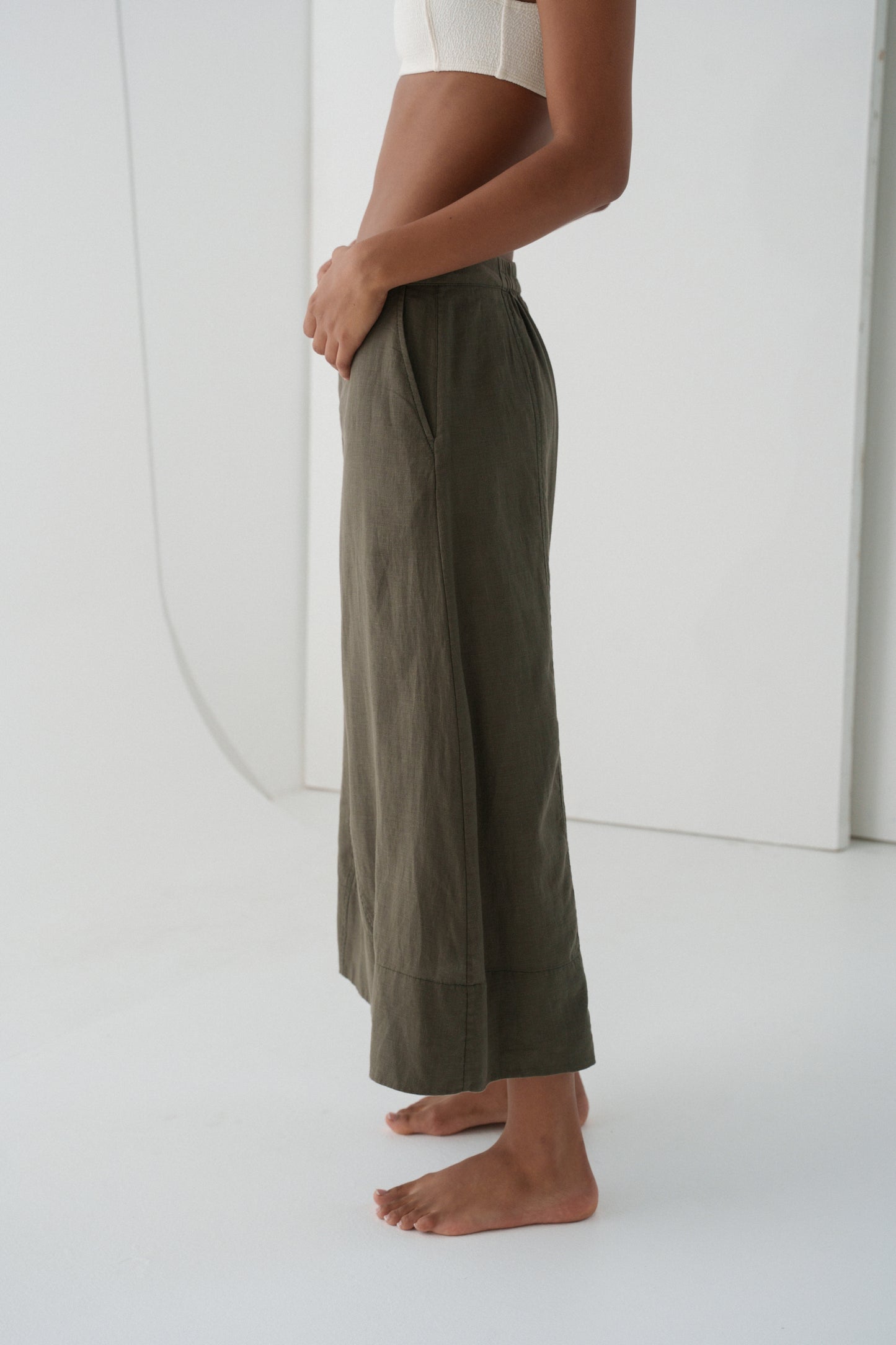 Side view close up of woman wearing khaki green Gia linen skirt against a white background