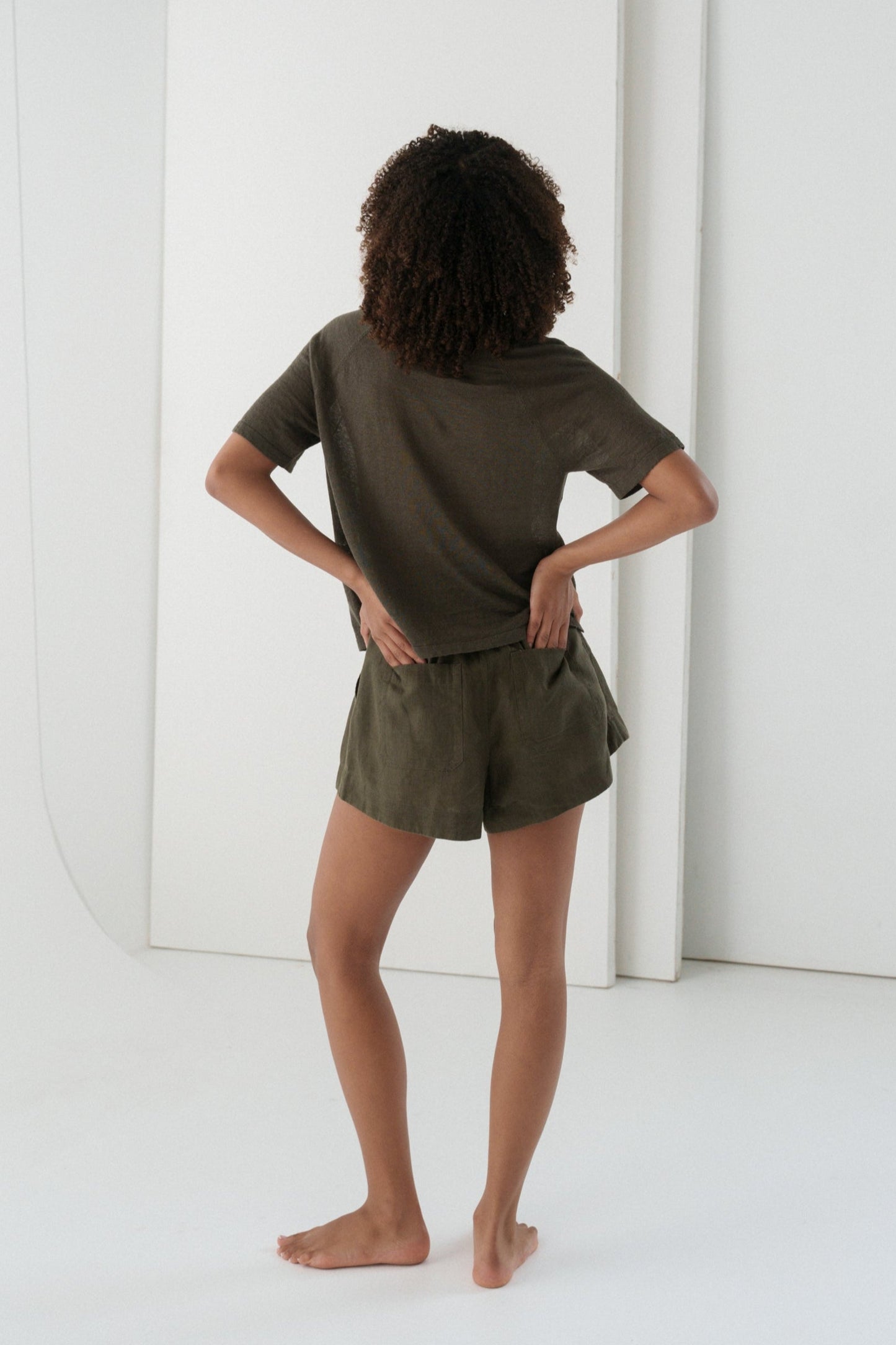 Woman wearing a khaki Grace linen knit top back view with white wall background