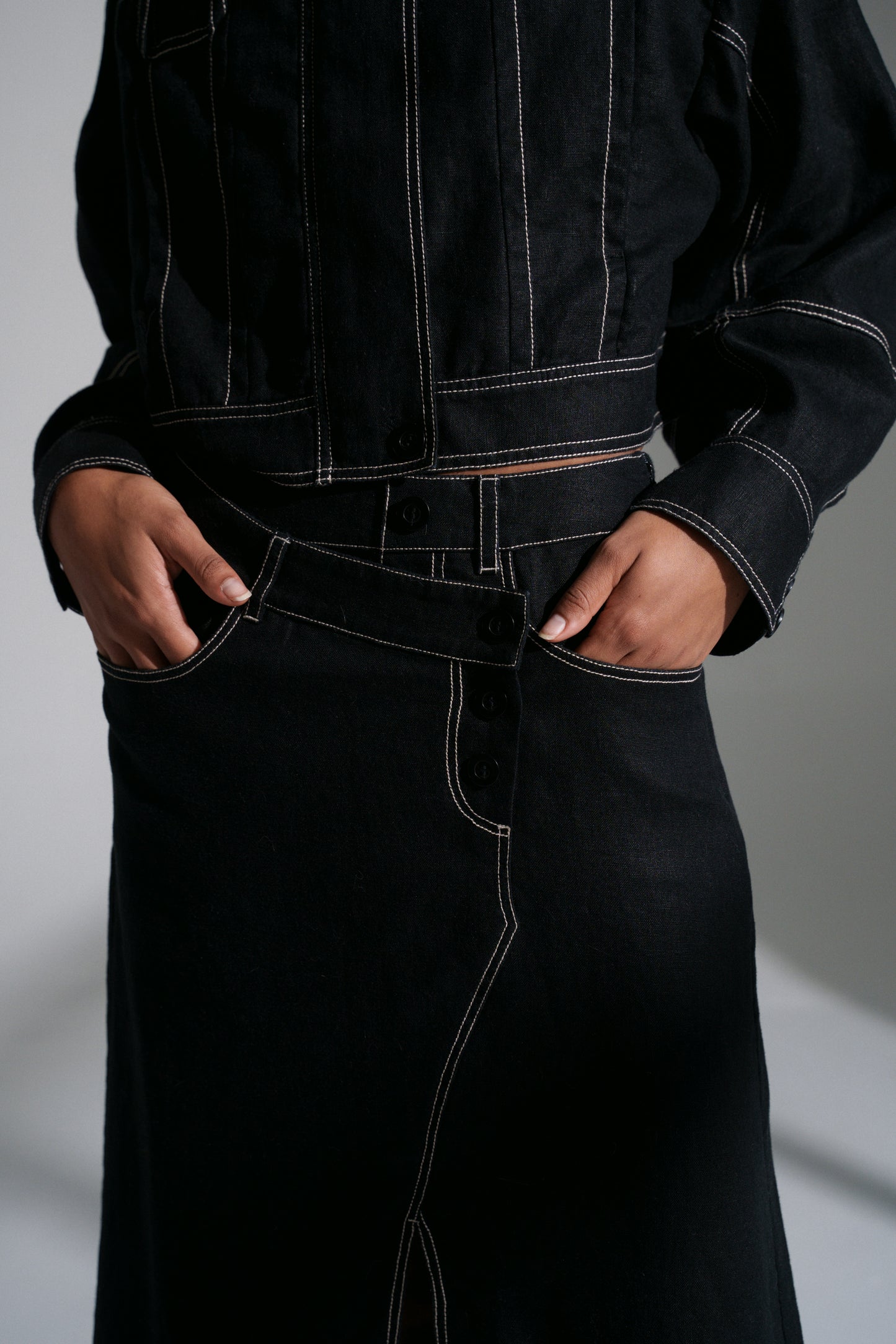 LILLY PILLY woman wearing a black Wes linen jacket and Jax linen skirt against a grey background