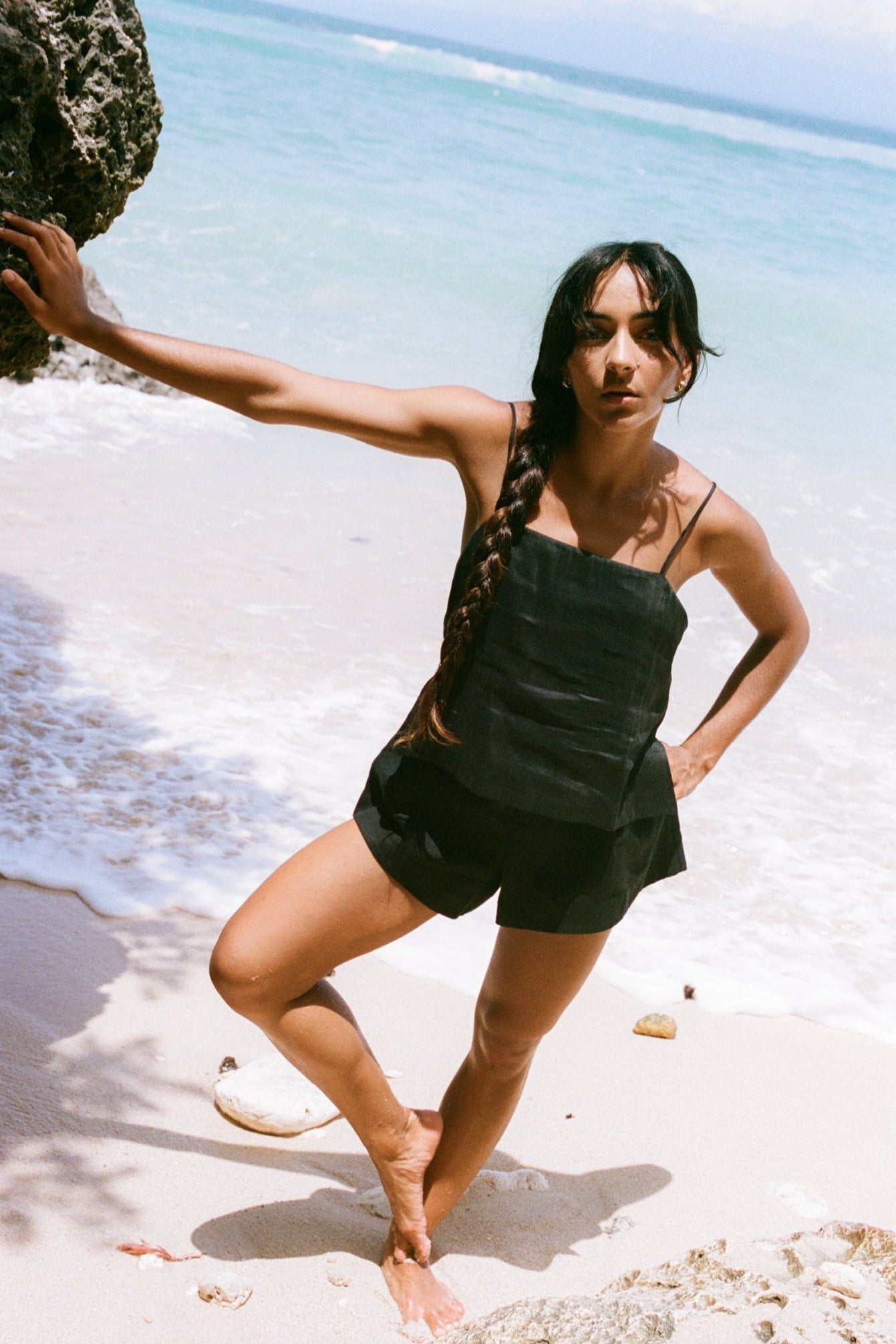 Rosa Linen Silk Cami in Black - full length, square neckline and spaghetti straps, hand on hip, styled with matching black linen silk shorts, sandy beach and ocean backdrop - Lilly Pilly Collection