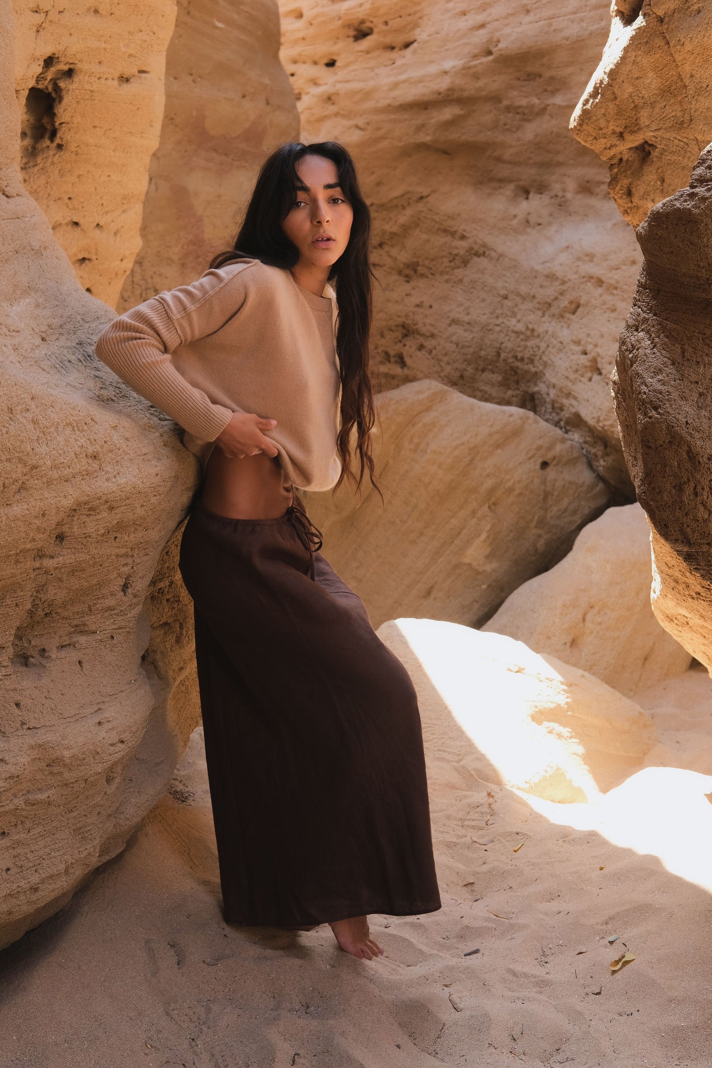 Riley Bias Linen Midi Skirt in Chocolate - woman wearing Chocolate linen skirt with camel Miri cashmere knit, natural rock formation - Lilly Pilly Collection