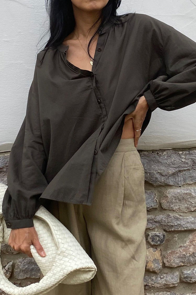 Ember Cotton Voile Shirt in Khaki - close-up of collar and button-front, gathered cuff, holding woven bag, brick wall backdrop - Lilly Pilly Collection