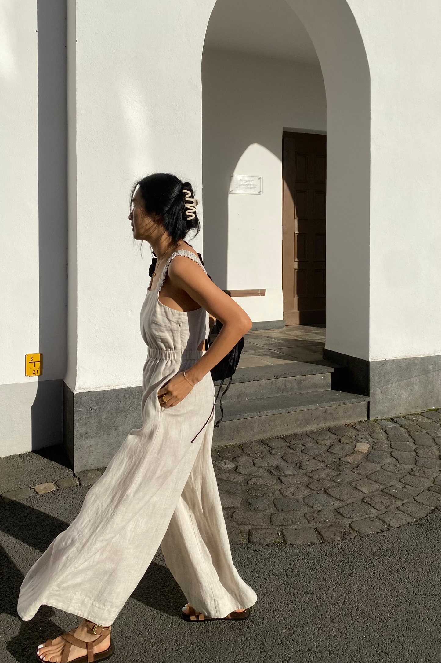 Side view of walking woman wearing the Keely Linen jumpsuit in Oatmeal - Lilly Pilly Collection