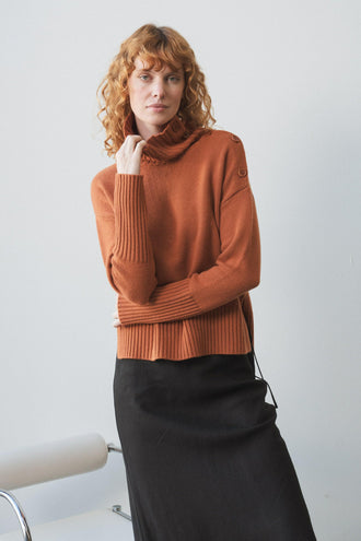 Kaida Cashmere Knit in Cajun Red - full front view paired with black Riley skirt standing by a white studio wall - Lilly Pilly Collection