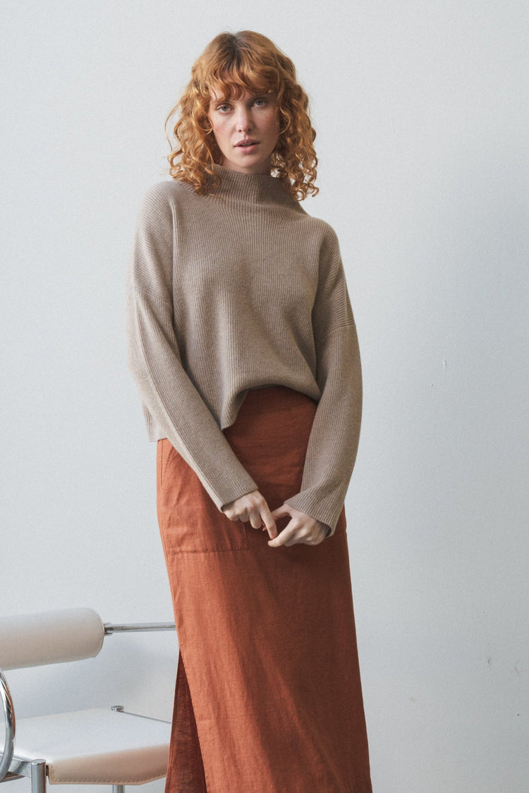 Lumi Cashmere Knit in Oatmeal - full length front view, funnel neckline, worn with rust skirt, studio setting - Lilly Pilly Collection