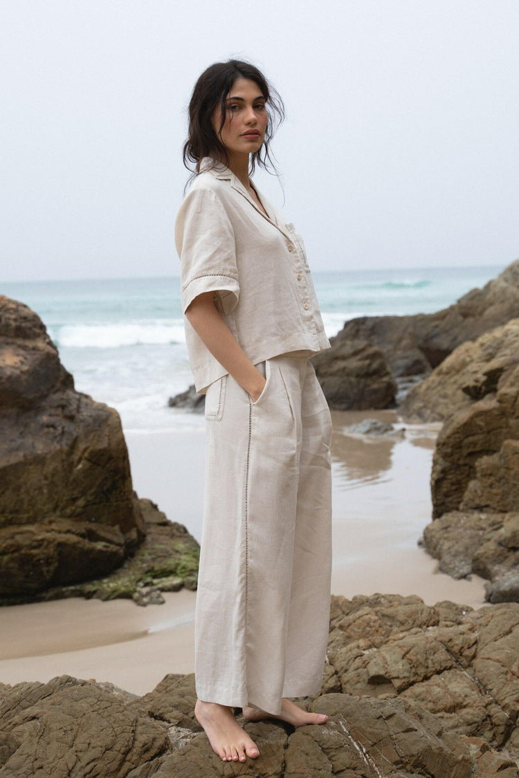 Rika Linen Pants in Chalk White - side view while standing on the rocks - Lilly Pilly Collection