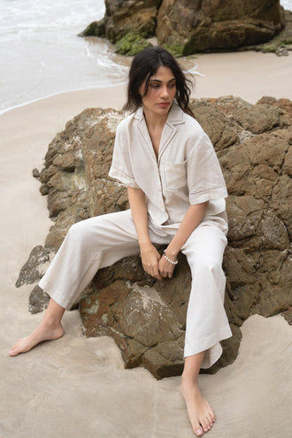 Quinn Linen Shirt in Chalk White - front view while seated on the rocks, paired with matching Rika pants - Lilly Pilly Collection