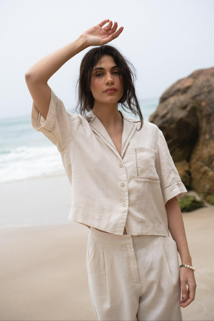 Quinn Linen Shirt in Chalk White - close up front view with hand over head on the beach - Lilly Pilly Collection