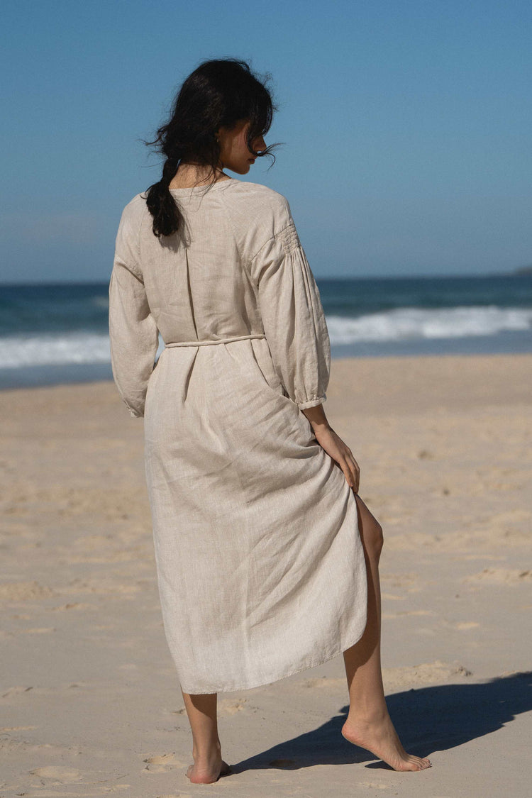 Skylar Linen Dress in Oatmeal - back view while standing on the beach - Lilly Pilly Collection