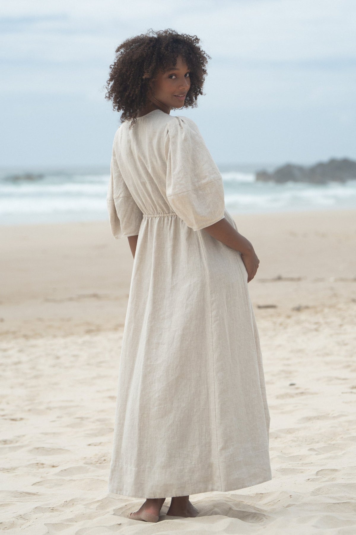 Back view of a woman wearing the Vida Linen maxi sleeve dress in Oatmeal - Lilly Pilly Collection