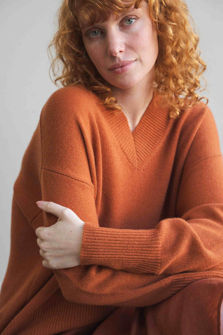 June Cashmere Knit in Cajun Red - close-up front view, V-neckline, arms crossed, studio setting - Lilly Pilly Collection