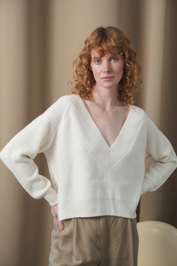 Cora Merino Knit in Ivory - front view, deep V-neckline, hand on hip, studio setting - Lilly Pilly Collection