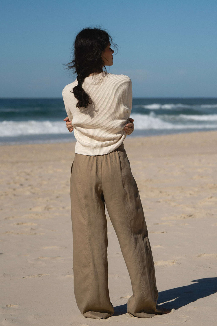 Bailey Cotton Cardigan in Cream - back view, ribbed knit detail, standing on beach with ocean backdrop - Lilly Pilly Collection