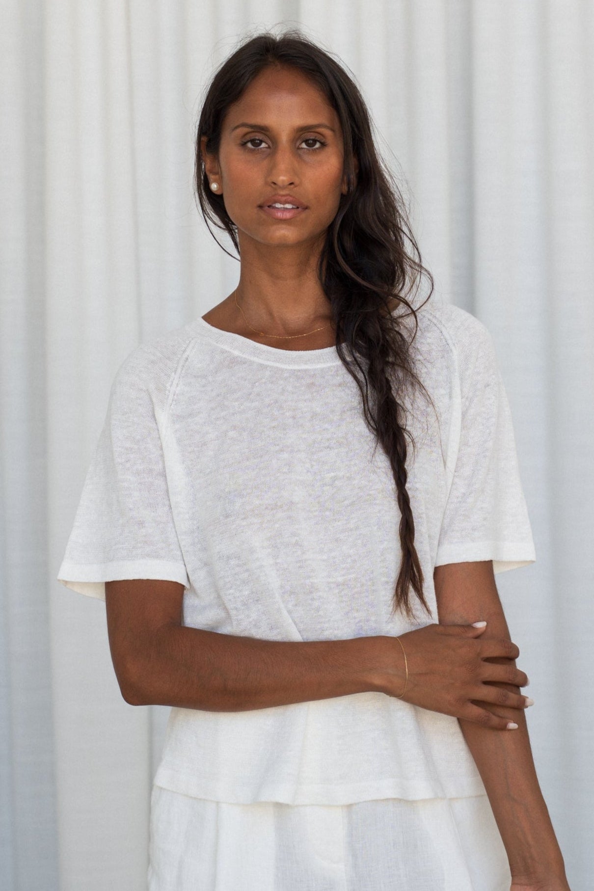 Person wearing a Grace knit top in Ivory against a curtain background