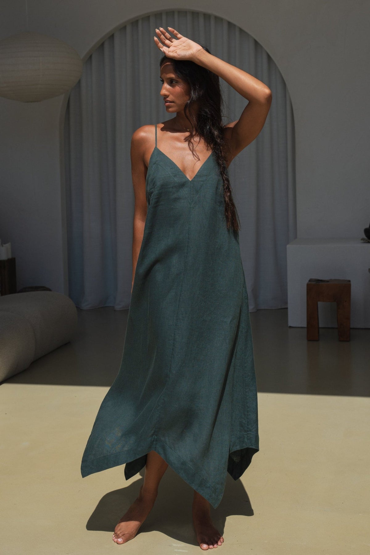 LILLY PILLY woman wearing a forest green Inez linen dress in a minimalistic room.