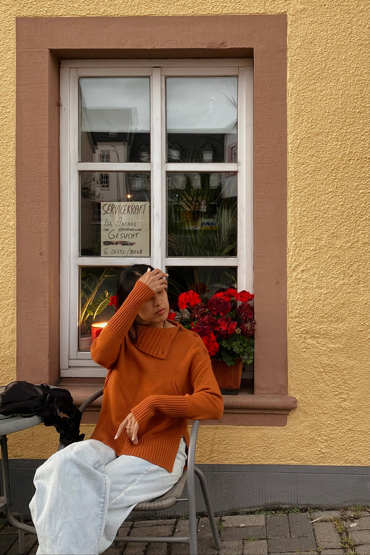 Kaida Cashmere Knit in Cajun Red - front view while seating in street cafe setting - Lilly Pilly Collection