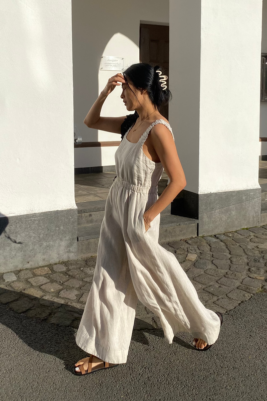 Walking woman wearing the Keely Linen jumpsuit in Oatmeal - Lilly Pilly Collection