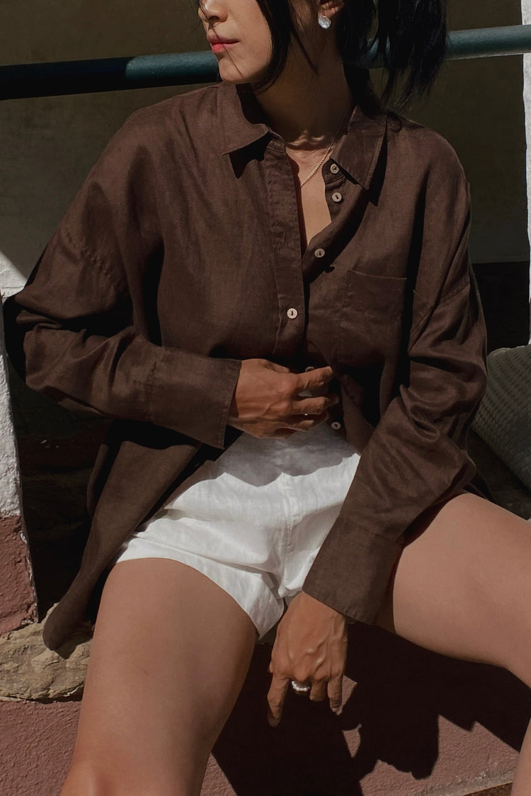 Kirra Linen Shirt in Chocolate - close-up, collared button-front and patch pocket, sitting, worn open over shorts - Lilly Pilly Collection