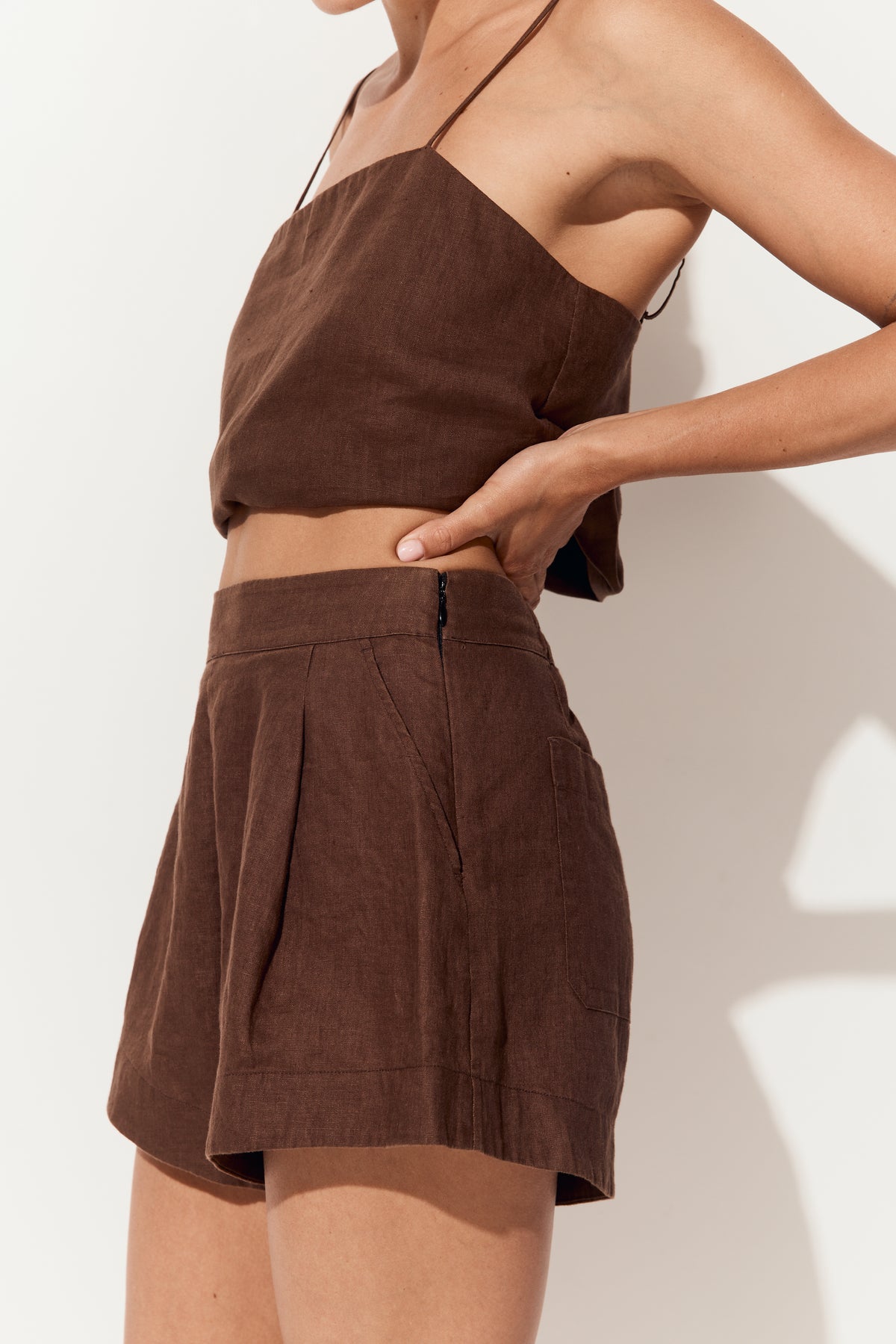 Gaia Linen Shorts in Chocolate - close up side view, touching waist with matching chocolate linen Rosa camisole - Lilly Pilly Collection