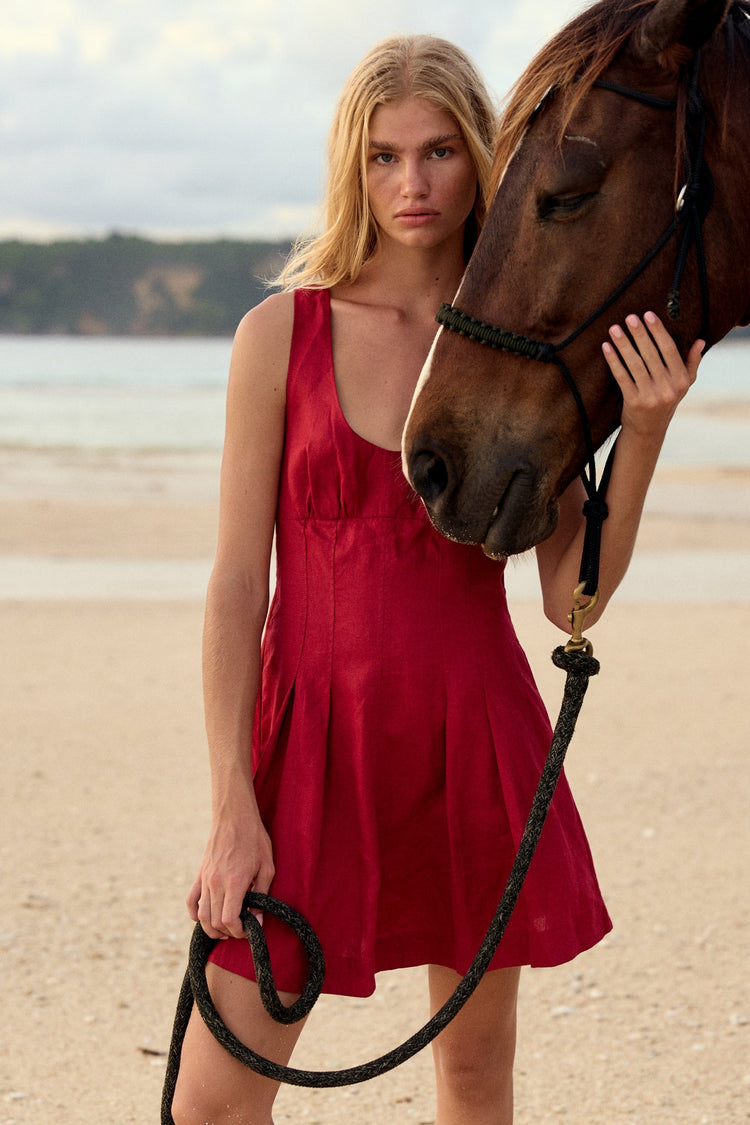 Adele Linen Short Dress in Cherry Red - woman on beach with horse, scoop neckline and pleated skirt - Lilly Pilly Collection