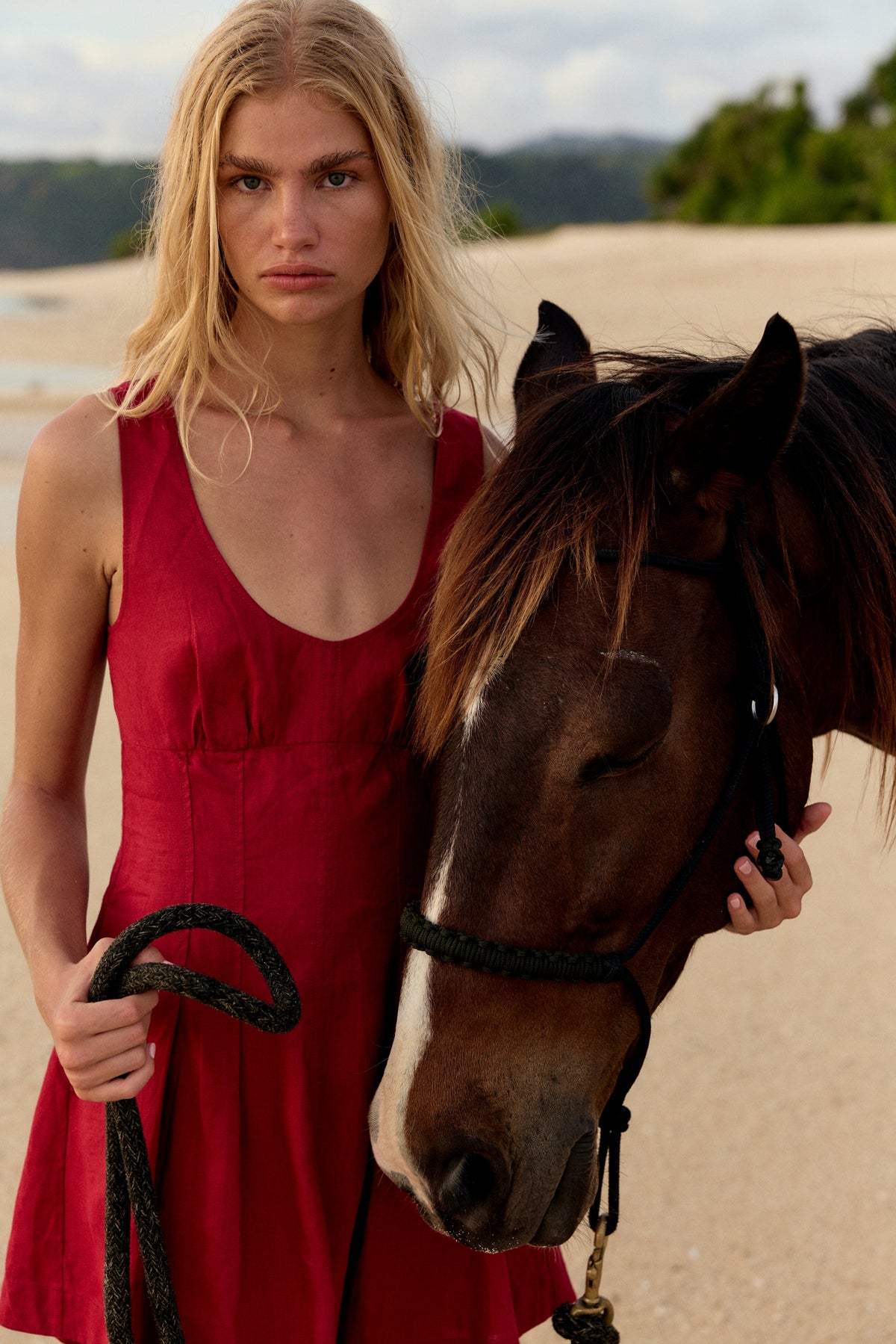 Adele Linen Short Dress in Cherry Red - close-up, woman beside horse on beach, scoop neckline detail - Lilly Pilly Collection