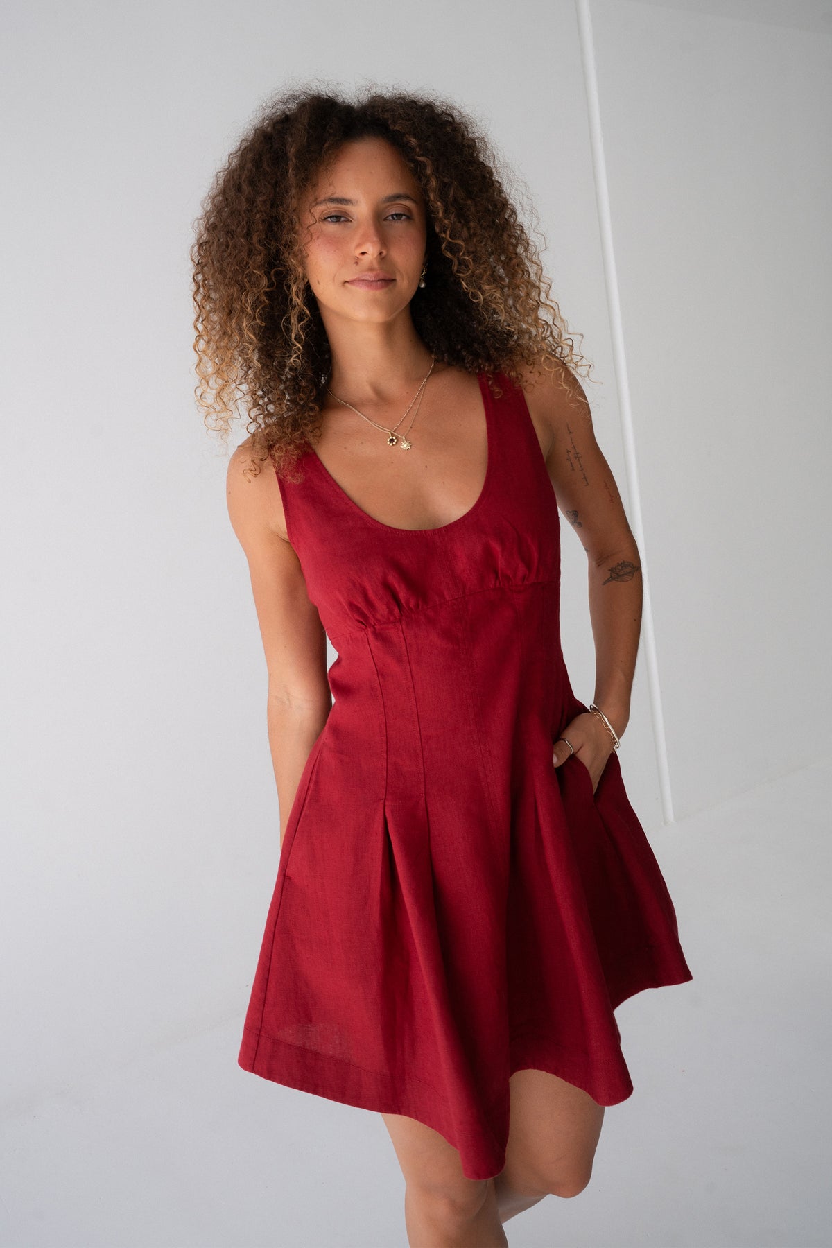 Adele Linen Short Dress in Cherry Red - full front view, scoop neckline and pleated A-line skirt, hand in pocket - Lilly Pilly Collection