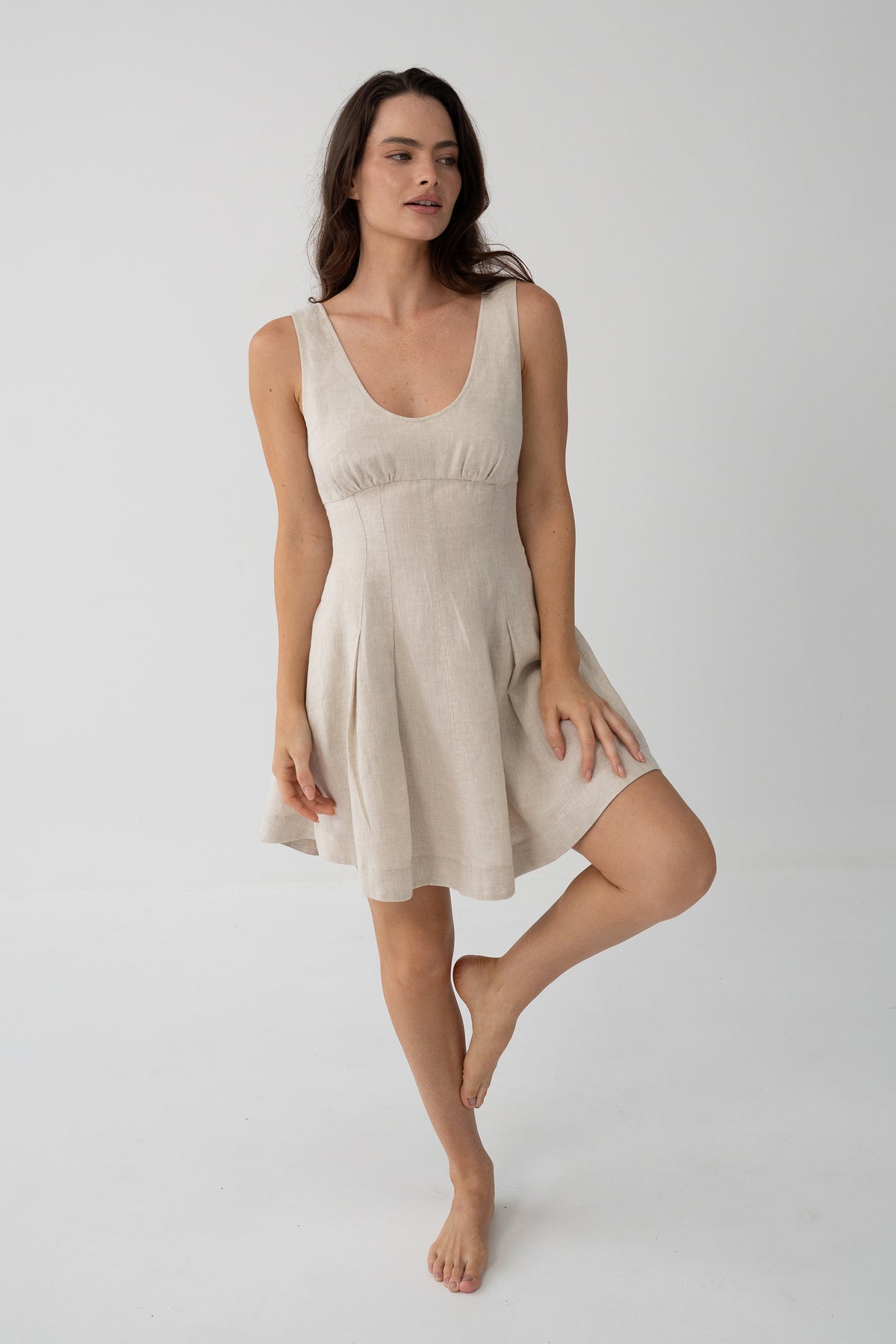 Adele Linen Short Dress in Oatmeal - three-quarter view, scoop neckline and fitted bodice, leg raised - Lilly Pilly Collection