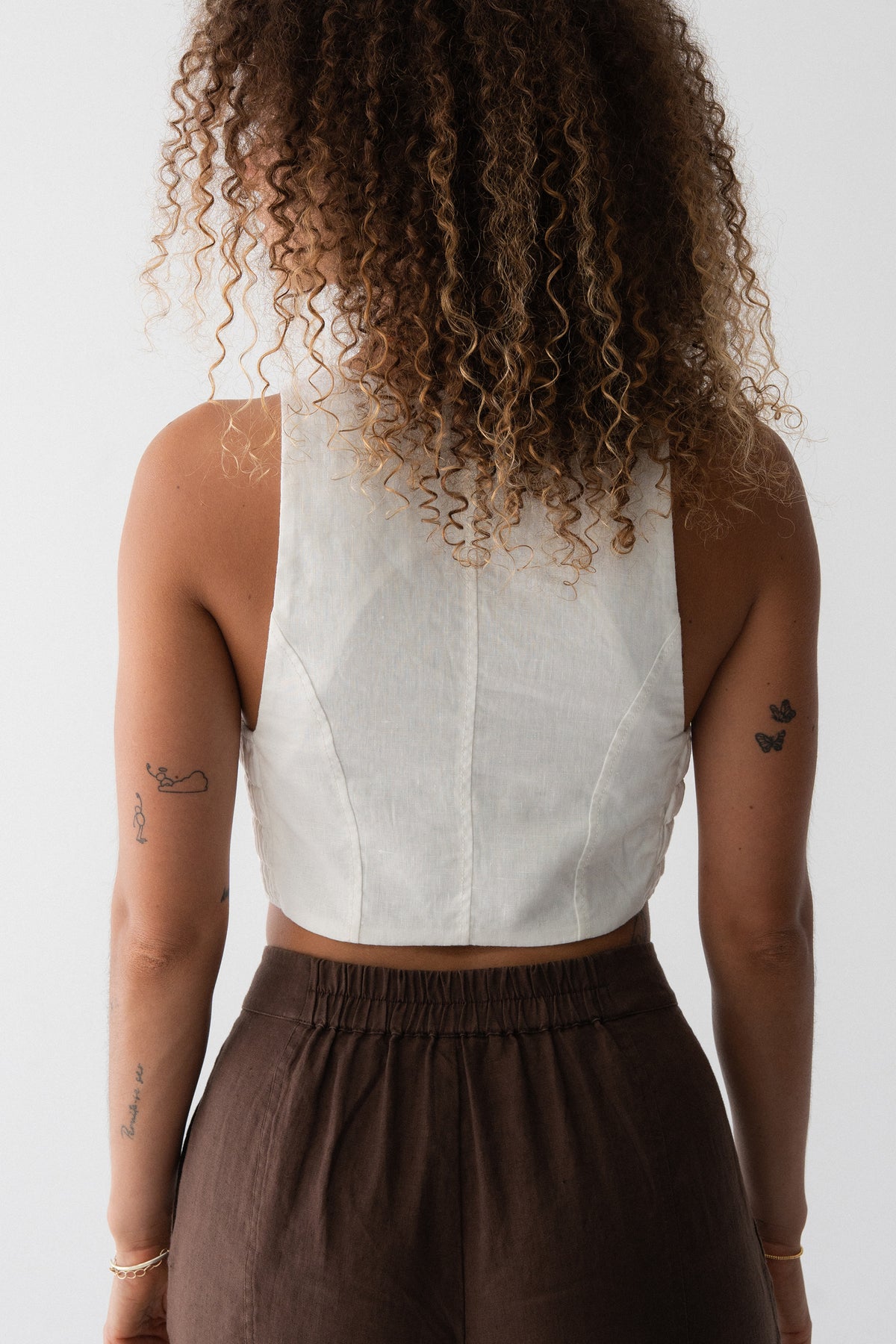 Ari Linen Vest in Ivory - back view, open racerback and shirred panel, styled with chocolate wide-leg linen pants - Lilly Pilly Collection