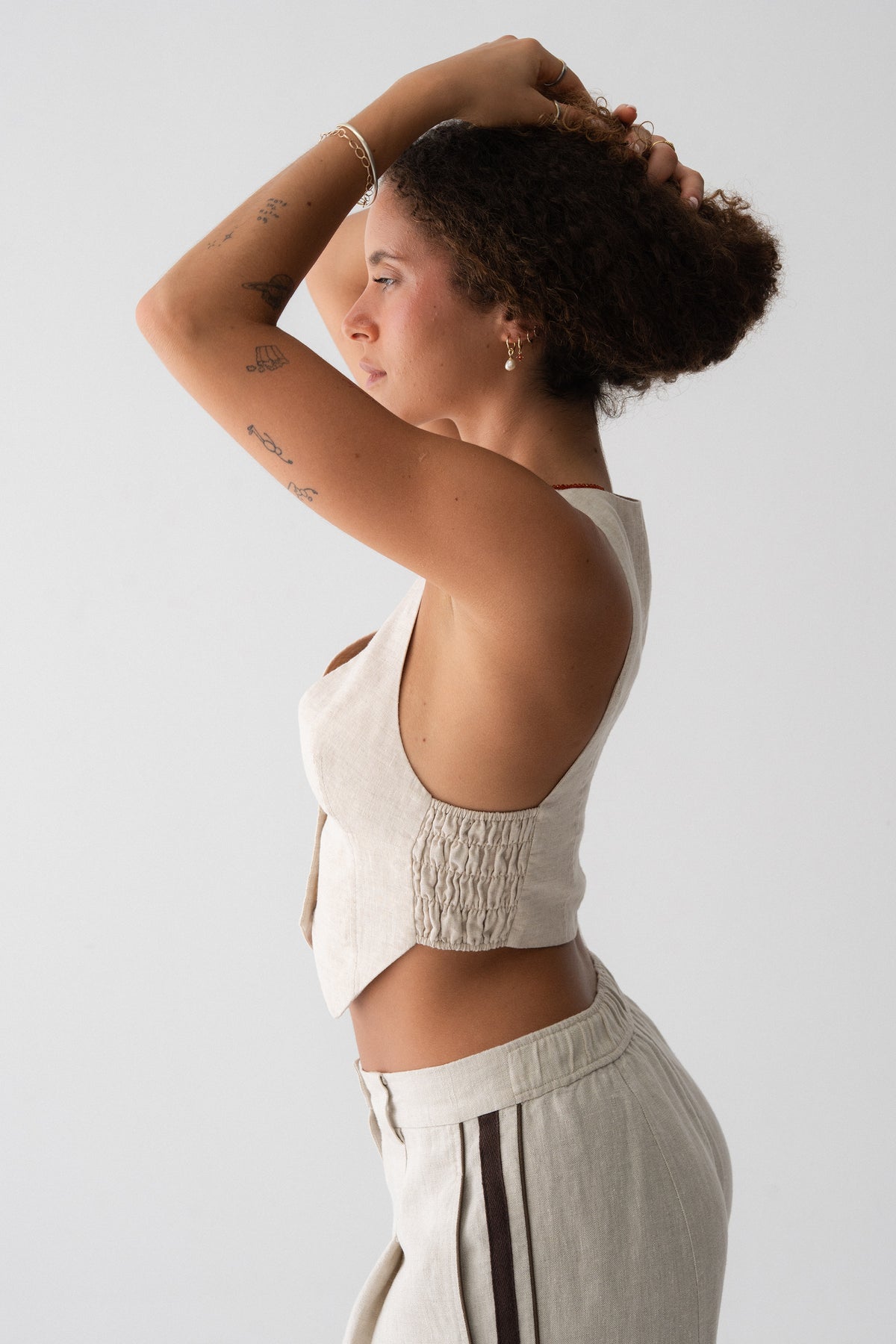 Ari Linen Vest in Oatmeal - side profile, open back and shirred back panel detail, styled with wide-leg linen pants - Lilly Pilly Collection