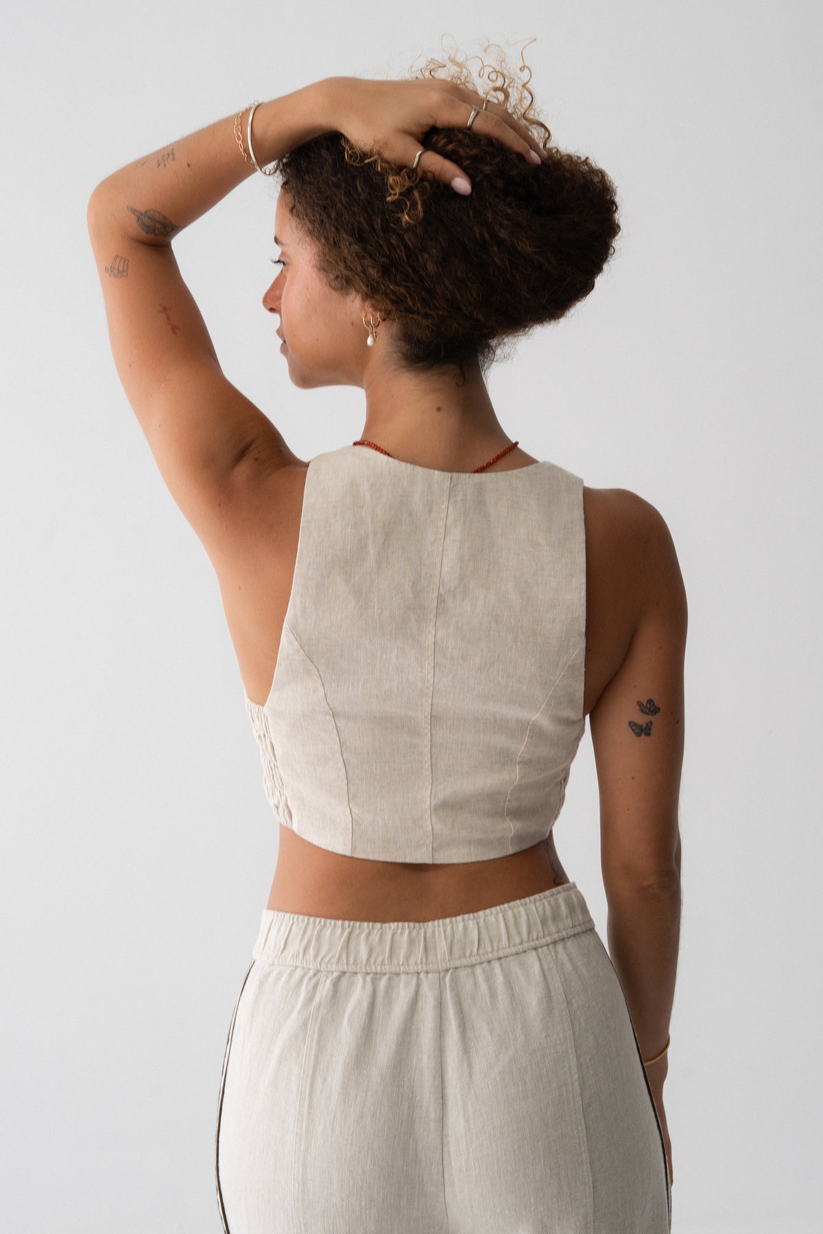 Ari Linen Vest in Oatmeal - back view, open racerback and shirred panel, styled with wide-leg linen pants - Lilly Pilly Collection