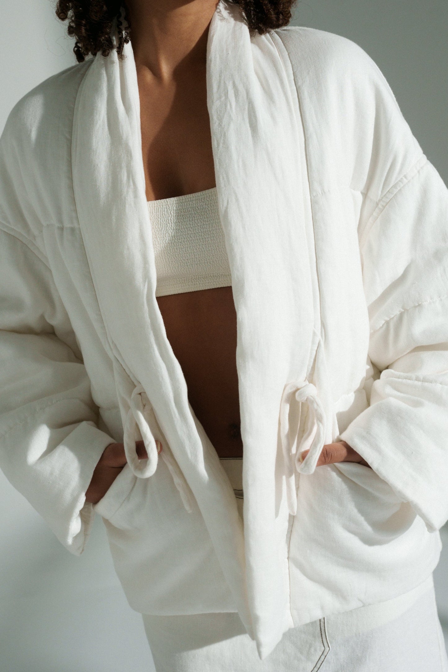 LILLY PILLY woman wearing Aster linen coat in ivory against a plain background