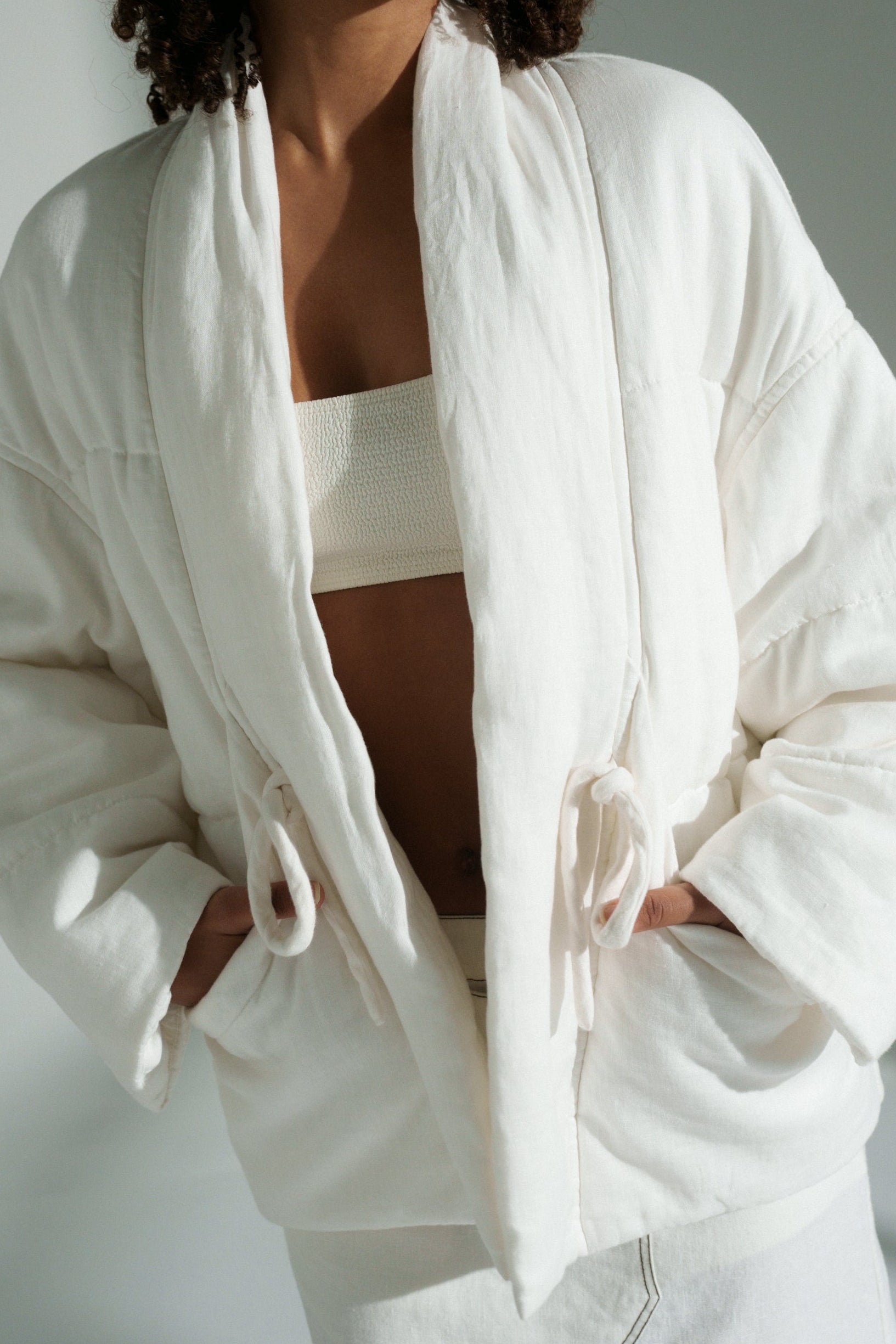 LILLY PILLY woman wearing Aster linen coat in ivory against a plain background