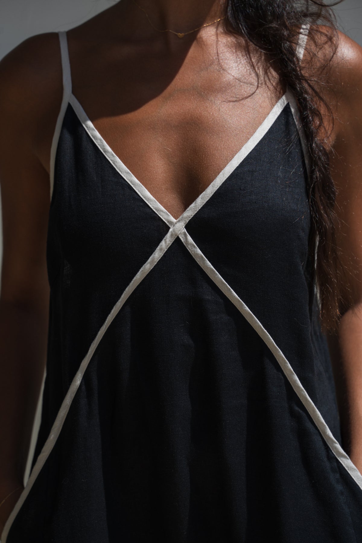LILLY PILLY woman in a Azalea black linen dress with close up of oatmeal garment details against a neutral background