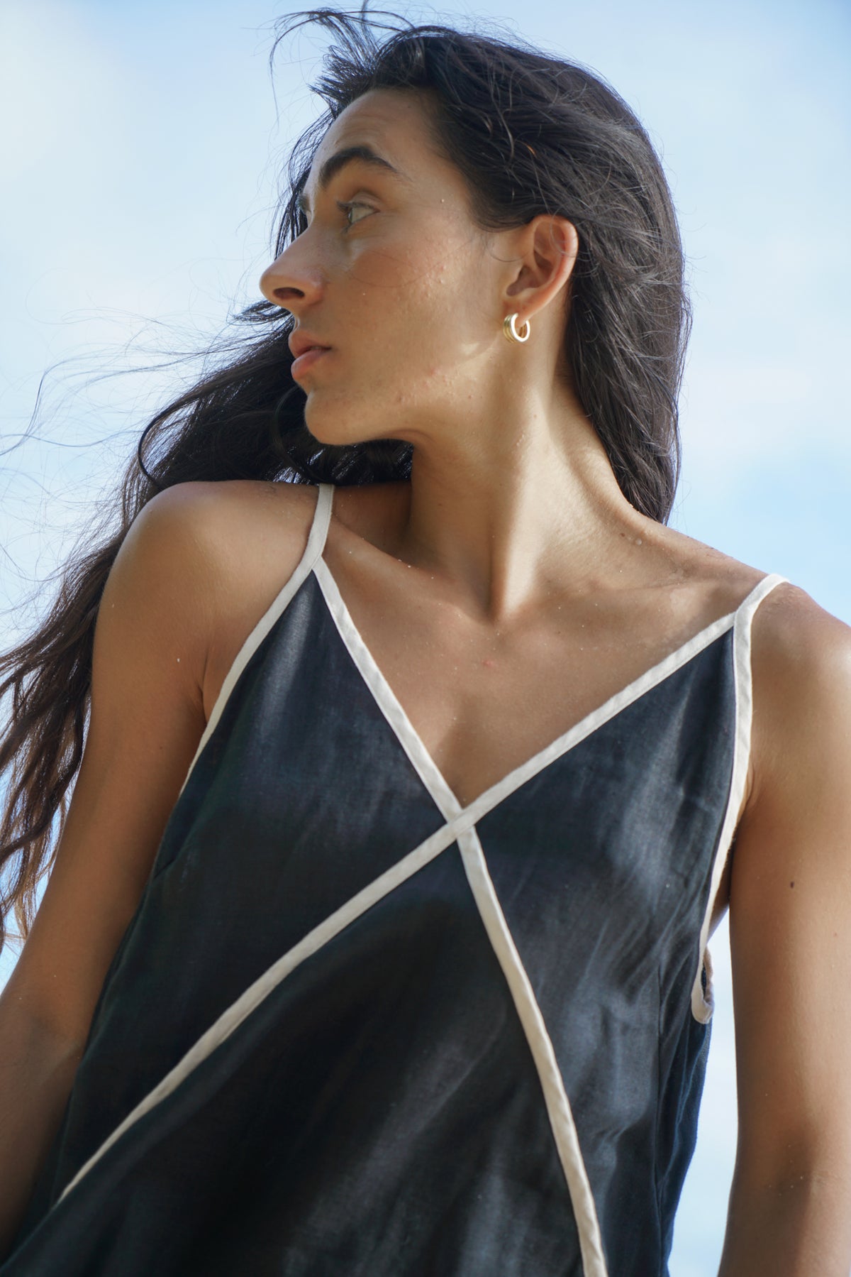 Close up of LILLY PILLY woman in a Azalea black linen dress showing the front garment details with ocean and sky in the background