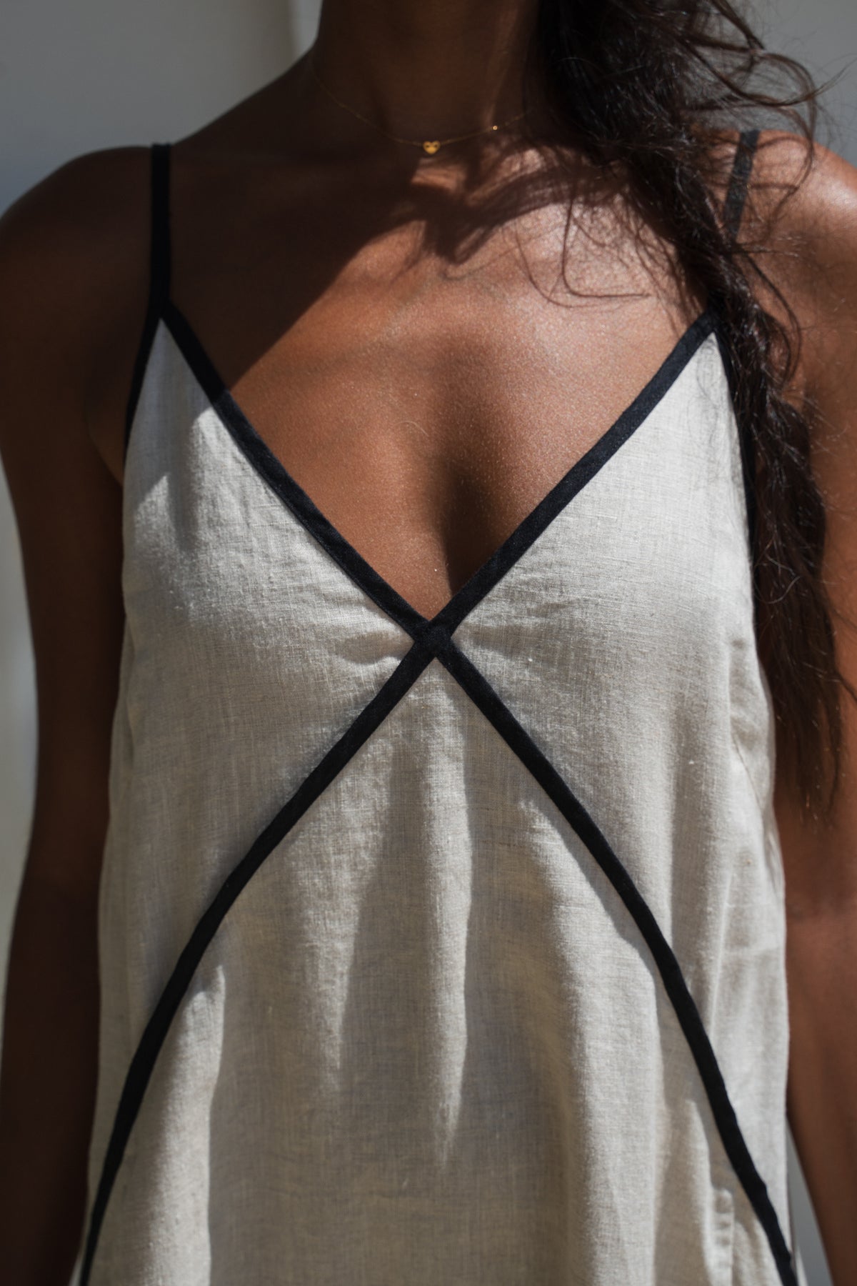 Close up front view of Lilly Pilly woman wearing an oatmeal Azalea dress with black straps and trim against a neutral background