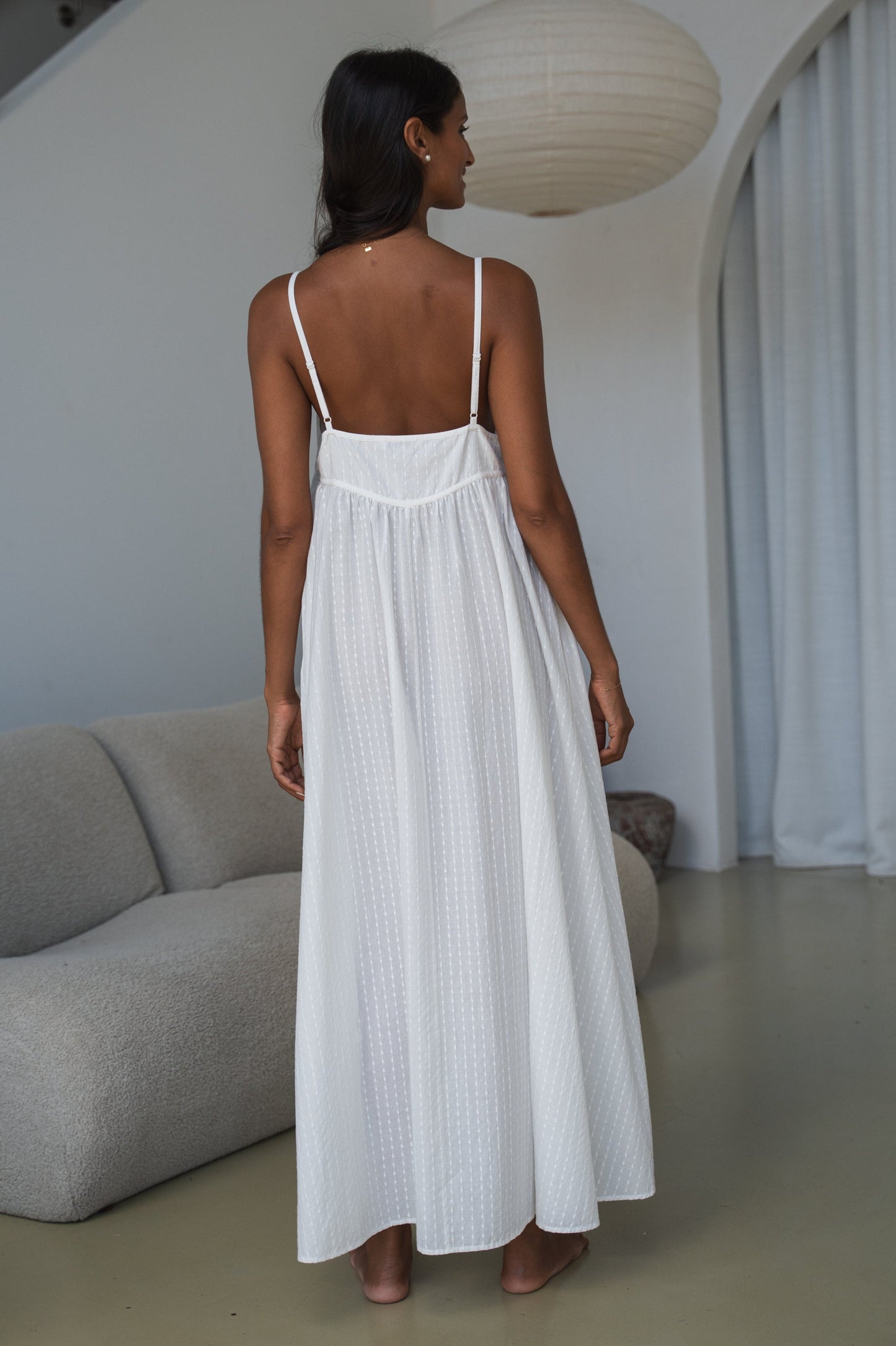 Woman in a white dress standing in a modern interior setting
