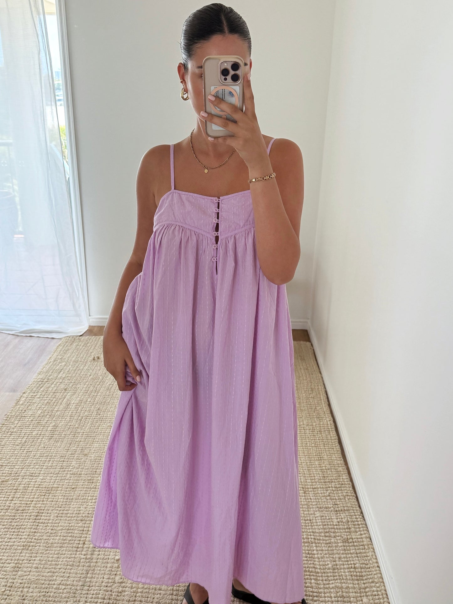 Woman wearing a light purple dress taking a mirror selfie.