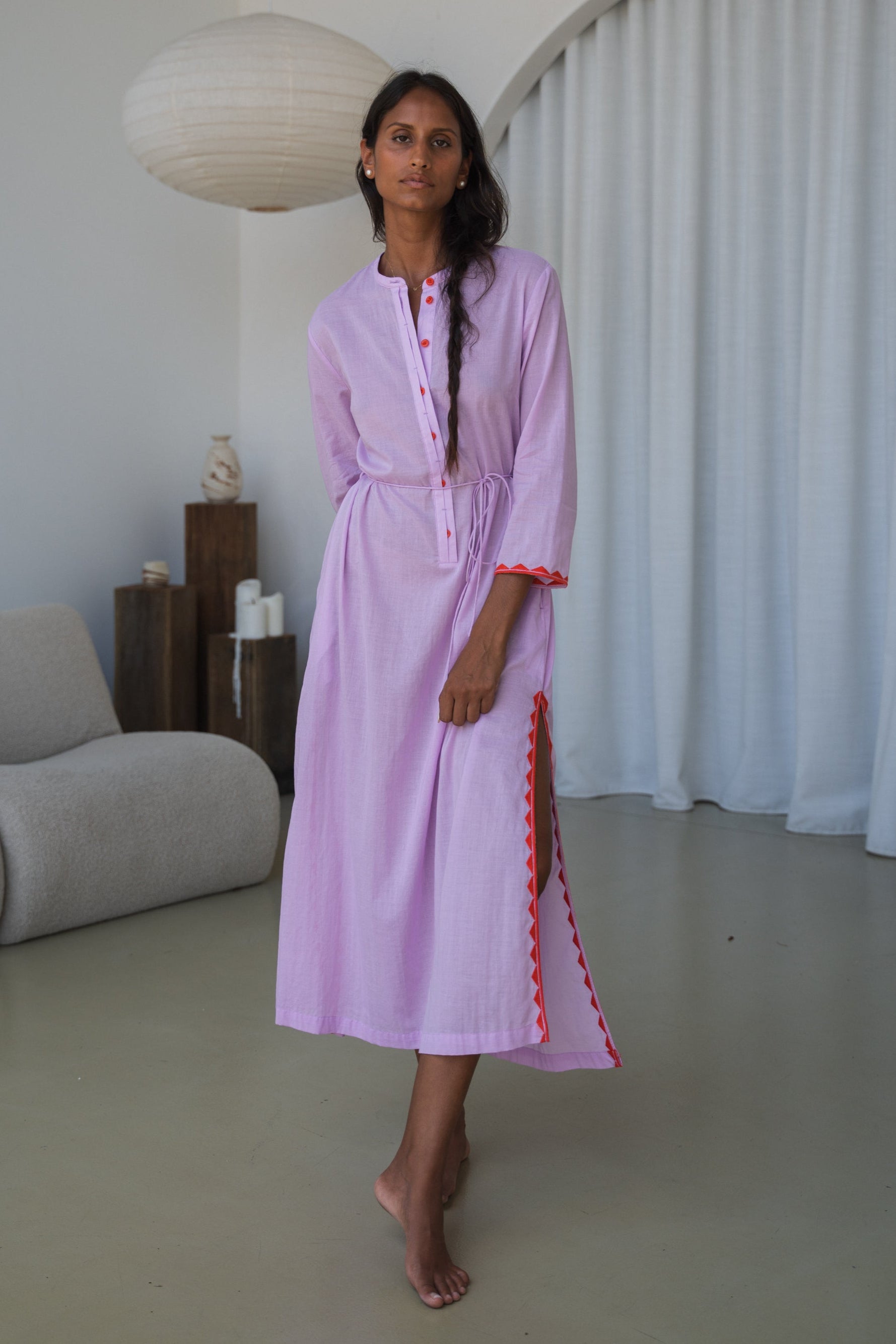 LILLY PILLY woman in a orchid Callie cotton dress standing in a minimalistic room.