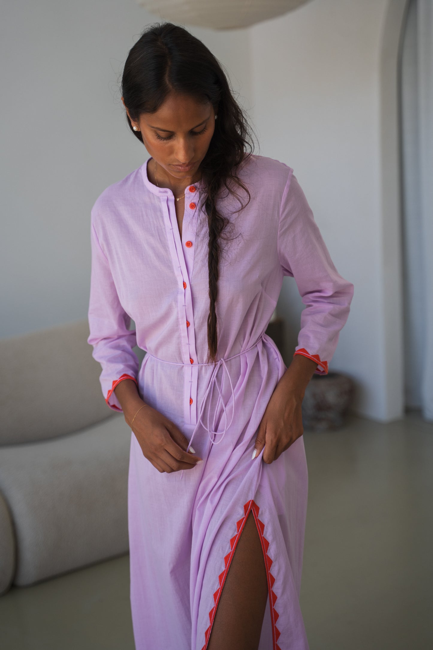 LILLY PILLY woman in a orchid Callie cotton dress standing in a minimalistic room showing side view and leg split details