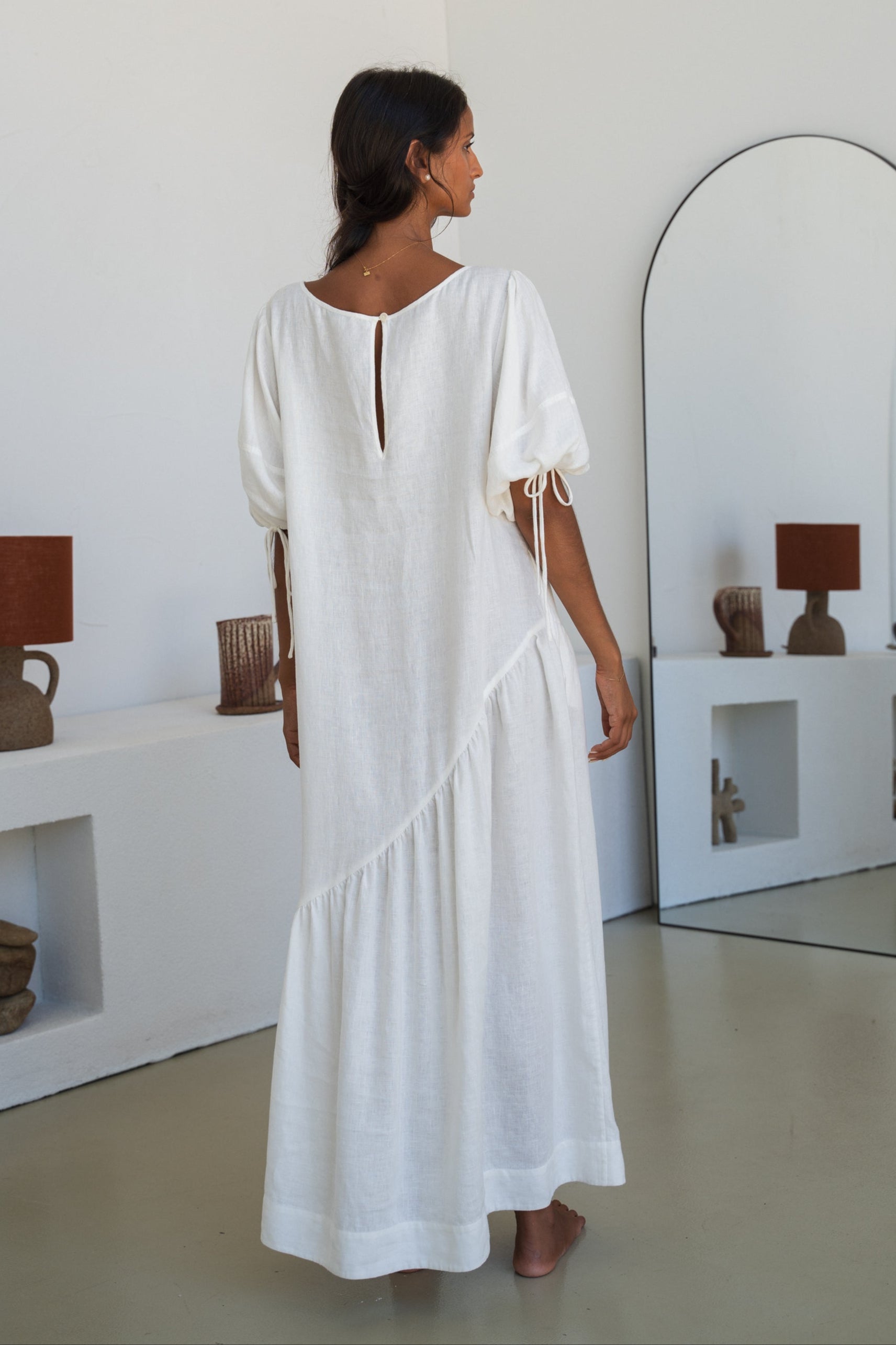 LILLY PILLY woman wearing Charlotte linen dress in Ivory standing facing a mirror