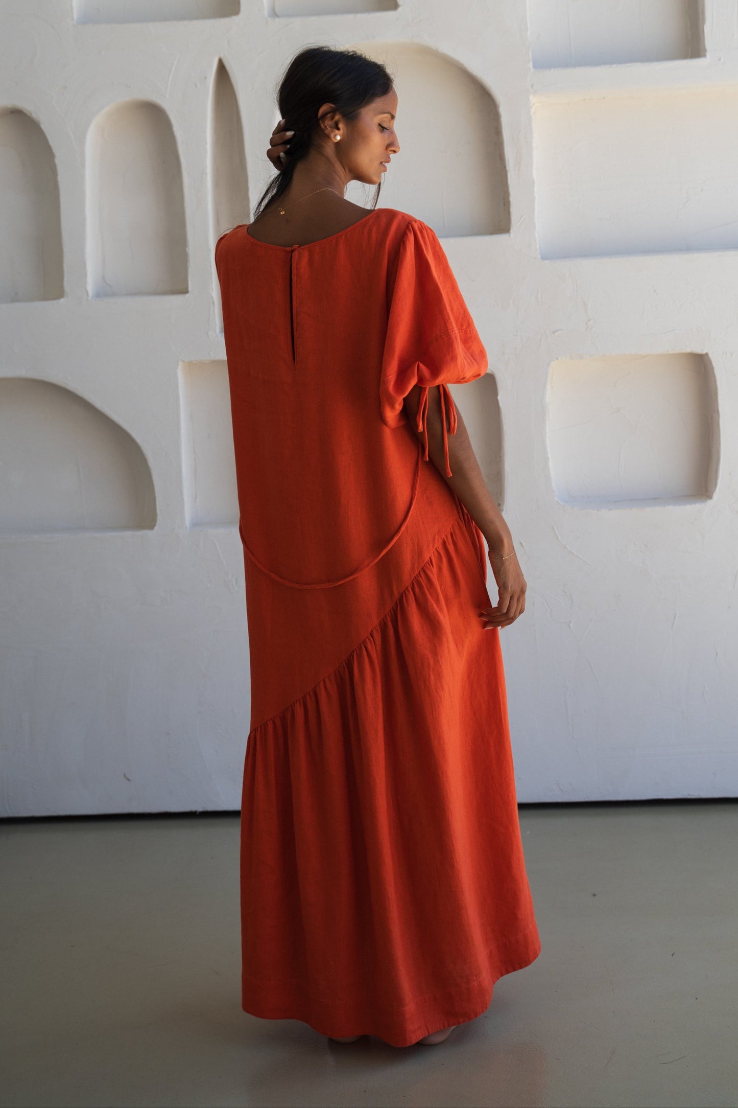 LILLY PILLY woman revealing back view of our spritz Charlotte linen dress against a textured wall