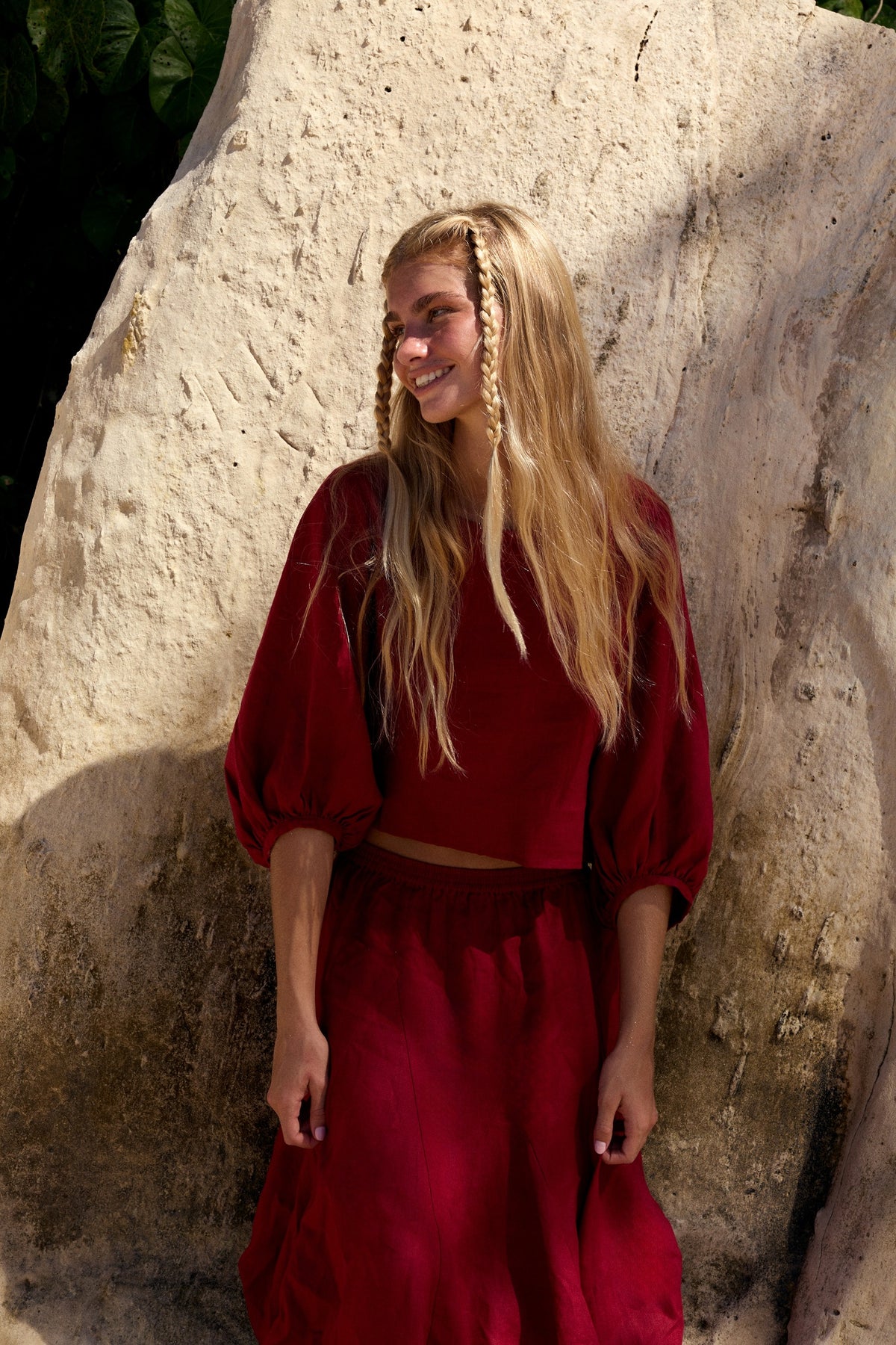 Demi Linen Top in Cherry Red - woman smiling against sandstone wall, round neckline and puff sleeves, styled with matching Riley Linen Skirt - Lilly Pilly Collection