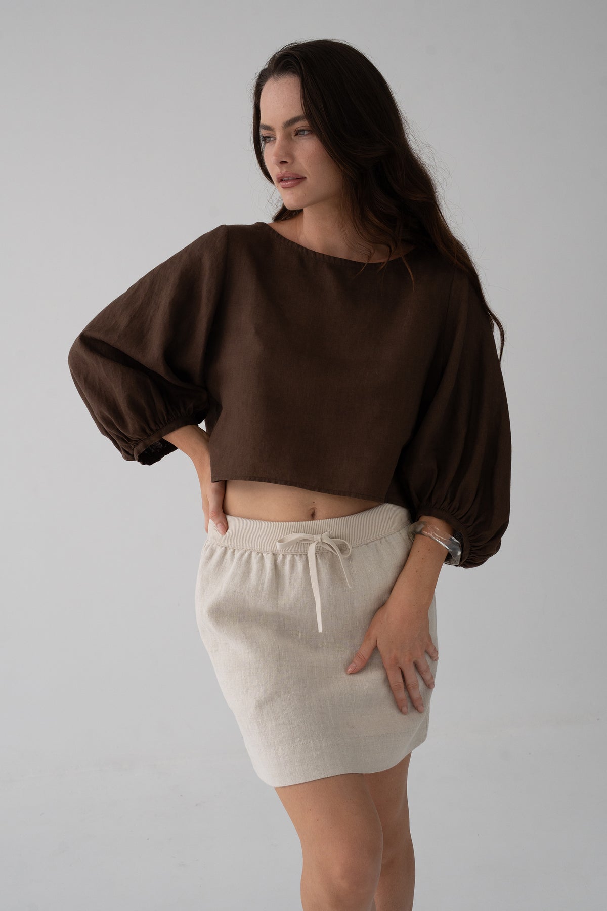 Demi Linen Top in Chocolate - three-quarter view, round neckline and puff sleeves, styled with oatmeal knit mini skirt - Lilly Pilly Collection