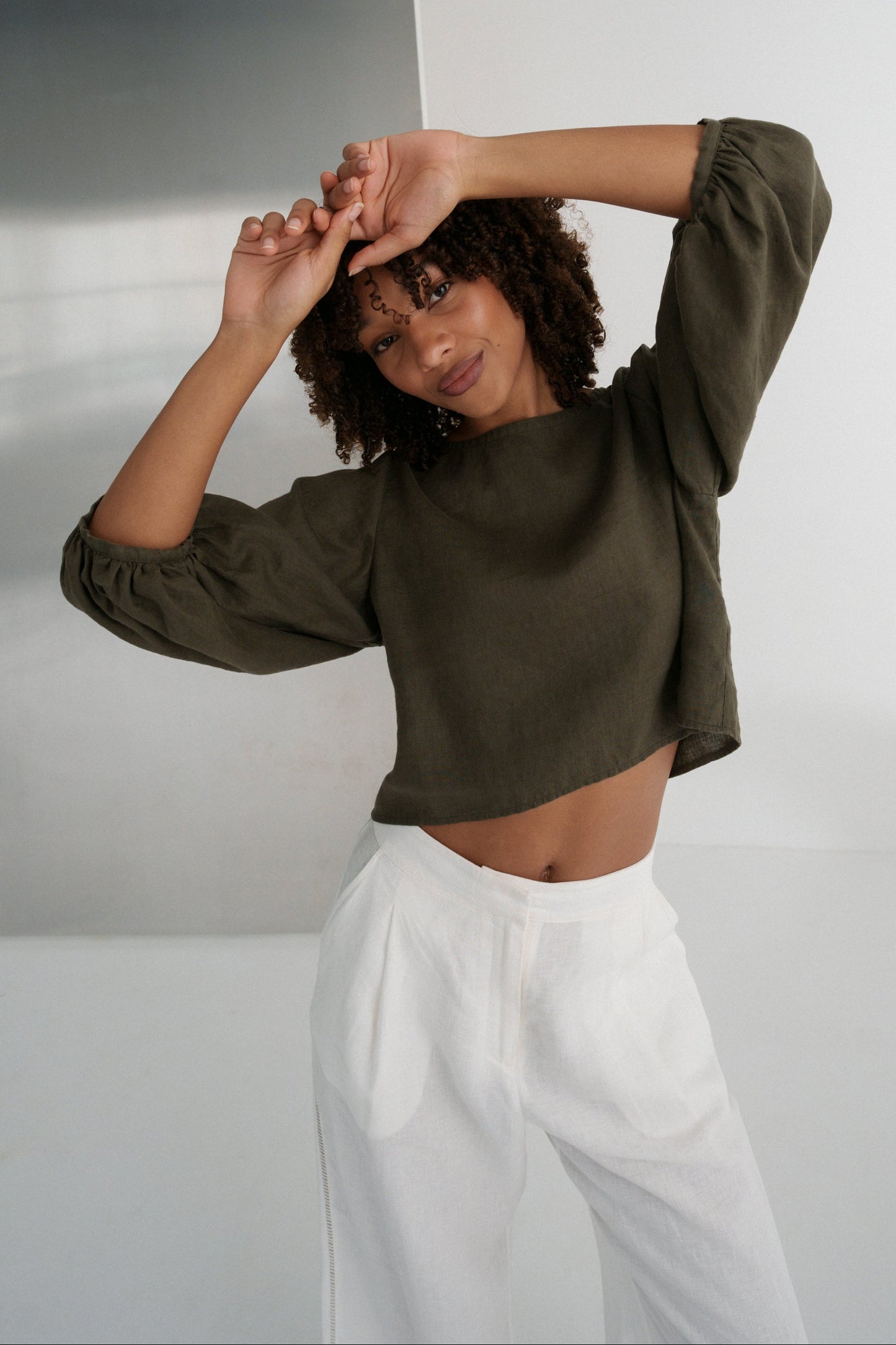 LILLY PILLY woman wearing a khaki green Demi linen top and ivory Oli linen pants against a plain background showing front view