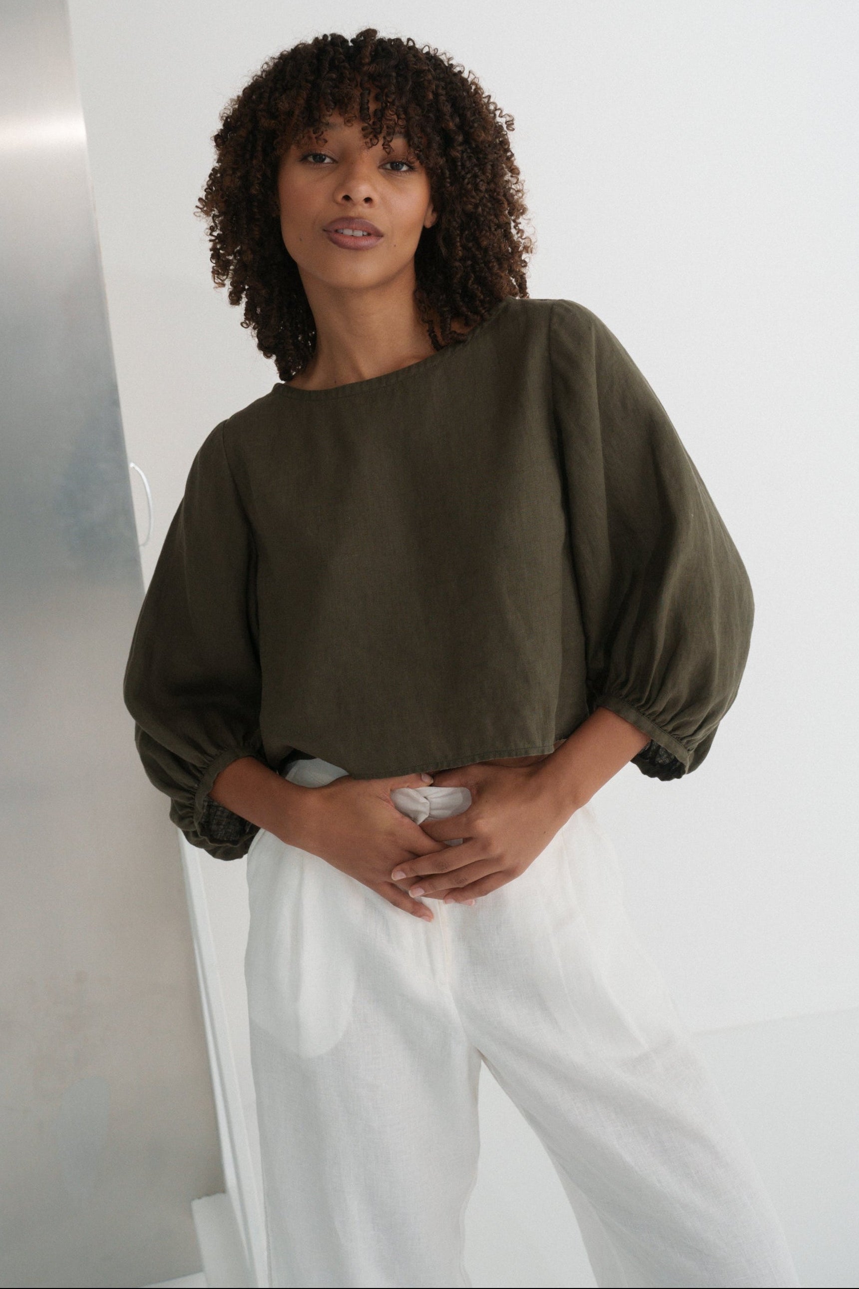 LILLY PILLY woman wearing a khaki green Demi linen top and ivory Ivy linen pants against a plain background