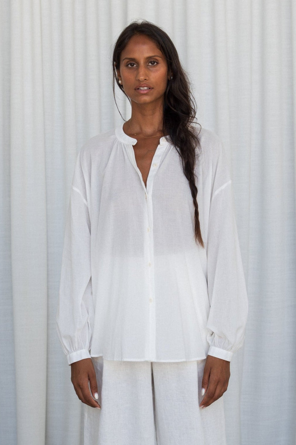 LILLY PILLY woman wearing a ivory Ember cotton voile shirt and ivory linen pants front view against a white background