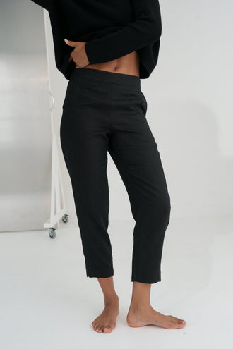 Emer Linen Pants in Black - close-up of flat waistband and tapered linen silhouette, studio backdrop - Lilly Pilly Collection