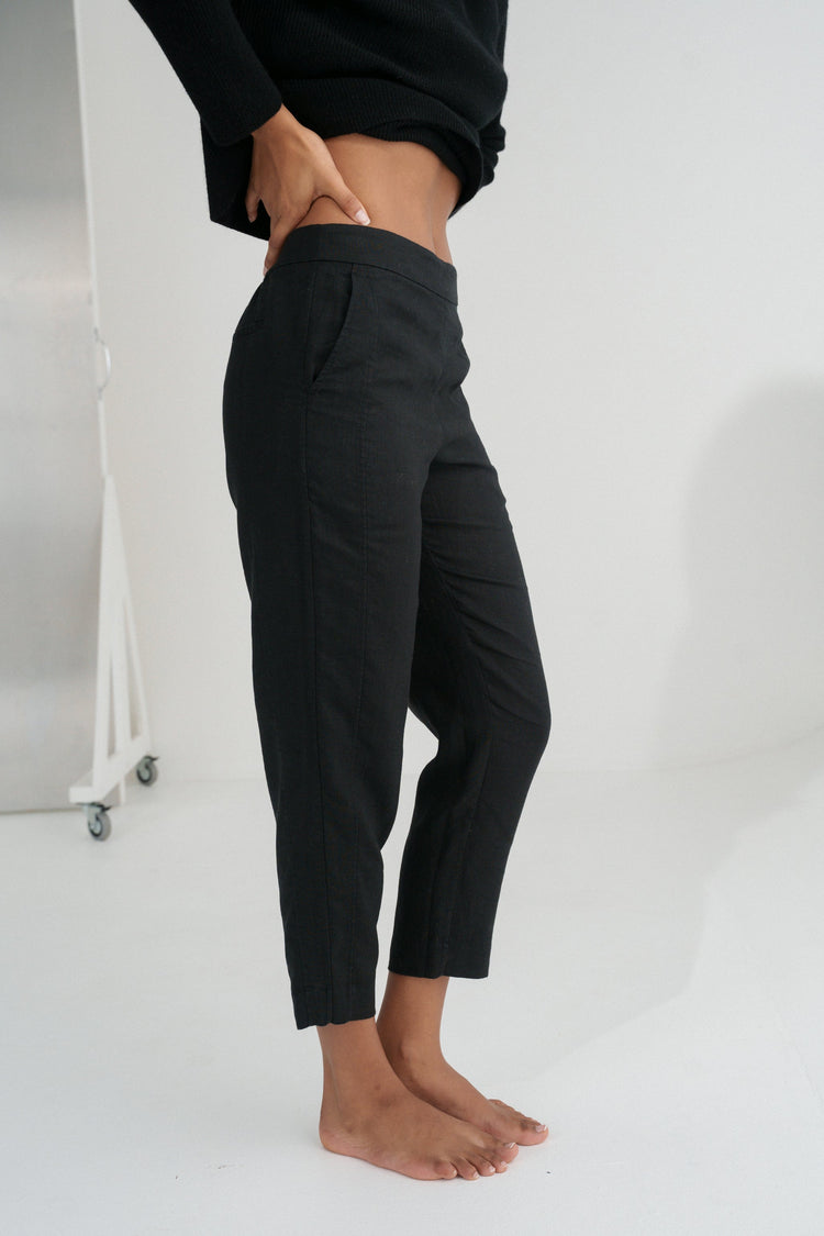 Emer Linen Pants in Black - side close-up of flat waistband and tapered linen leg, studio backdrop - Lilly Pilly Collection